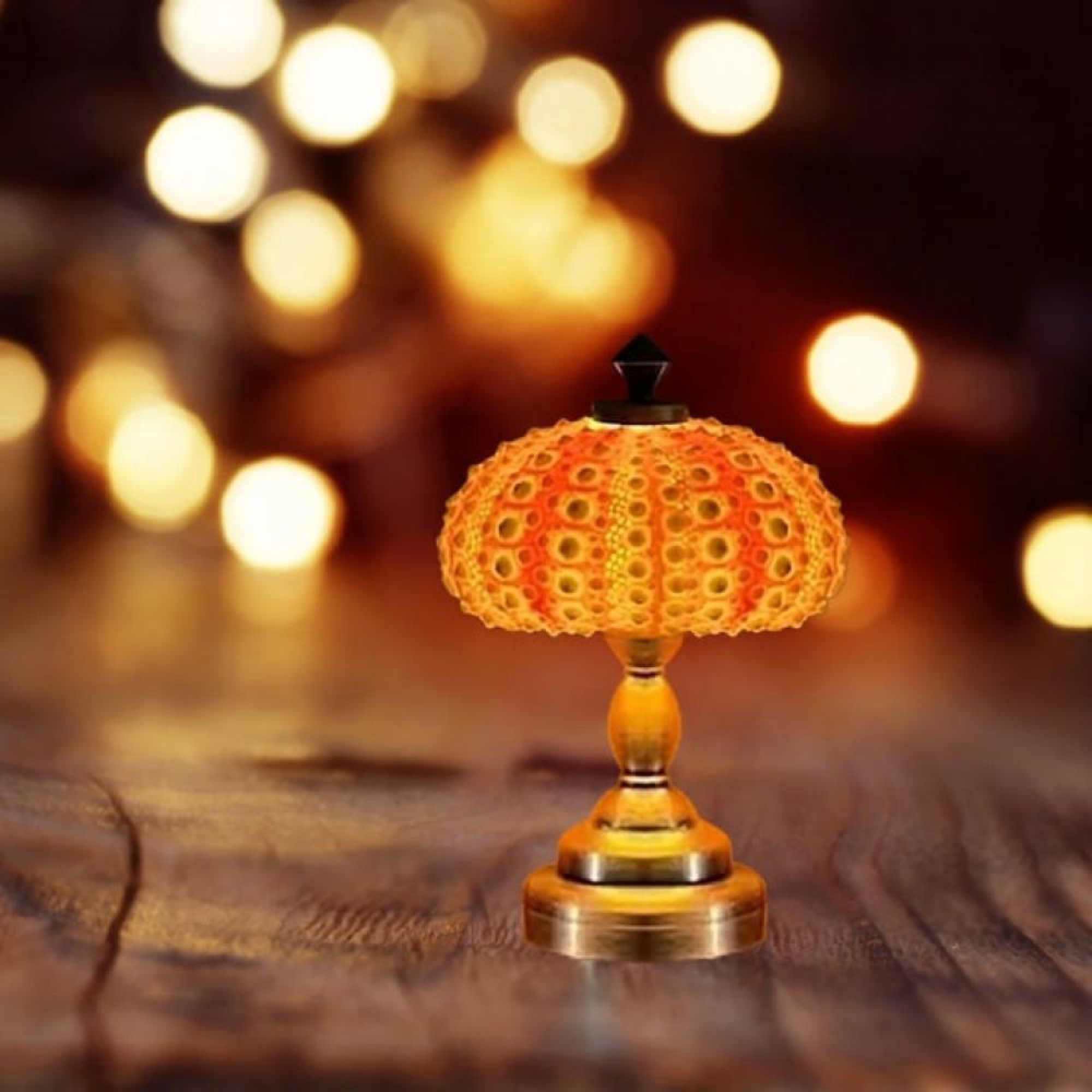 Eine Leuchtlampe mit orangefarbenem Schirm und Messingfuß steht auf einem Holztisch vor verschwommenen Lichtern.