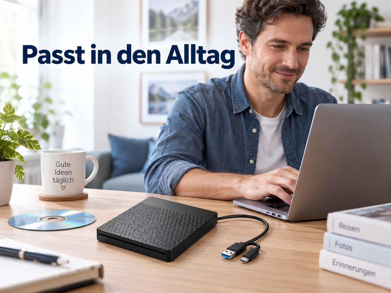 Ein Mann sitzt an einem Holztisch, arbeitet am Laptop. Vor ihm liegt ein schwarzes externes Laufwerk.