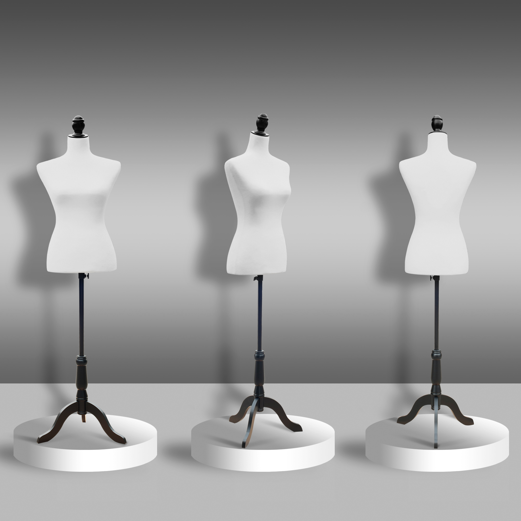 Tres maniquíes blancos con soportes negros se encuentran en plataformas redondas contra una pared gris.