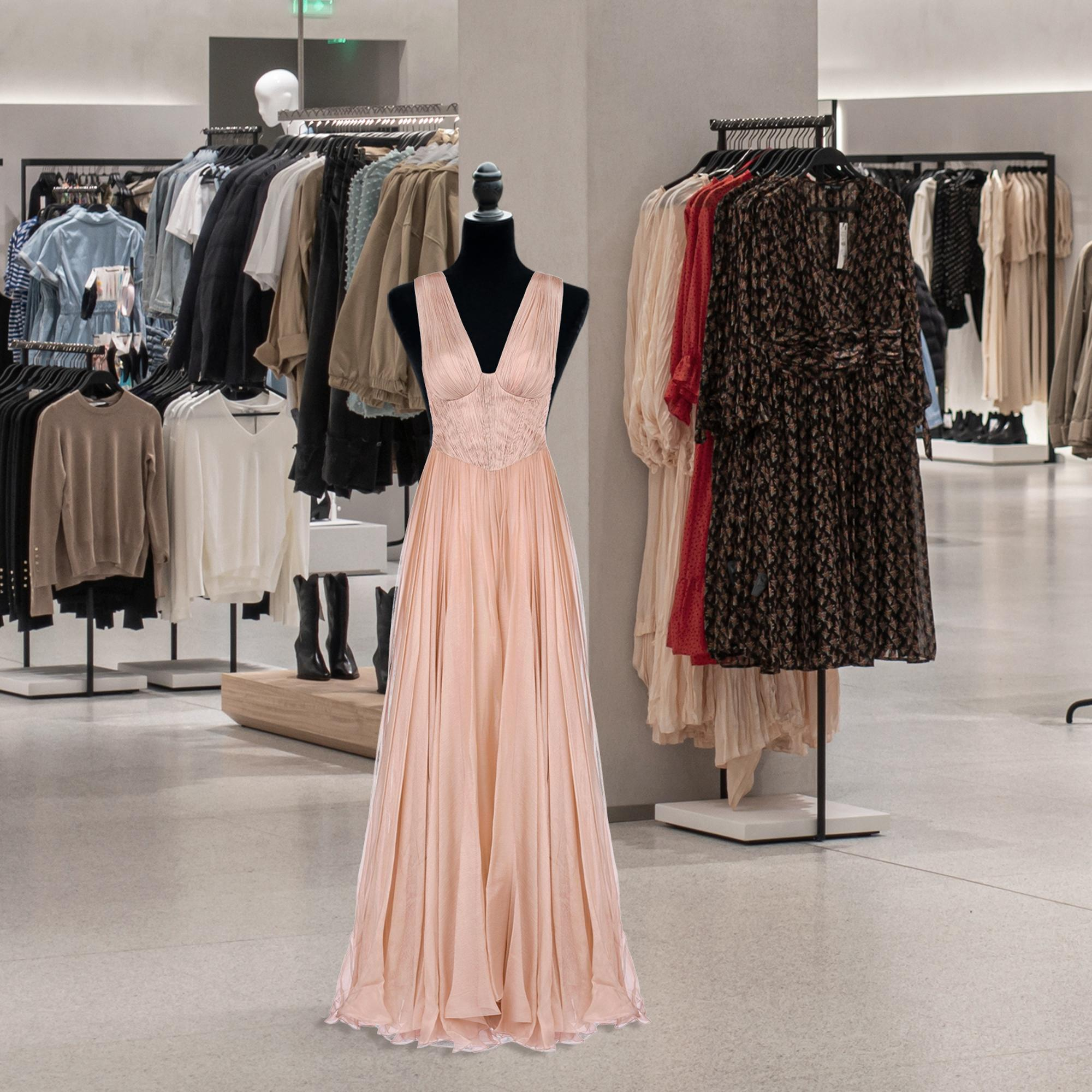 Un vestido de noche rosa sin mangas en un maniquí dentro de una tienda de ropa.