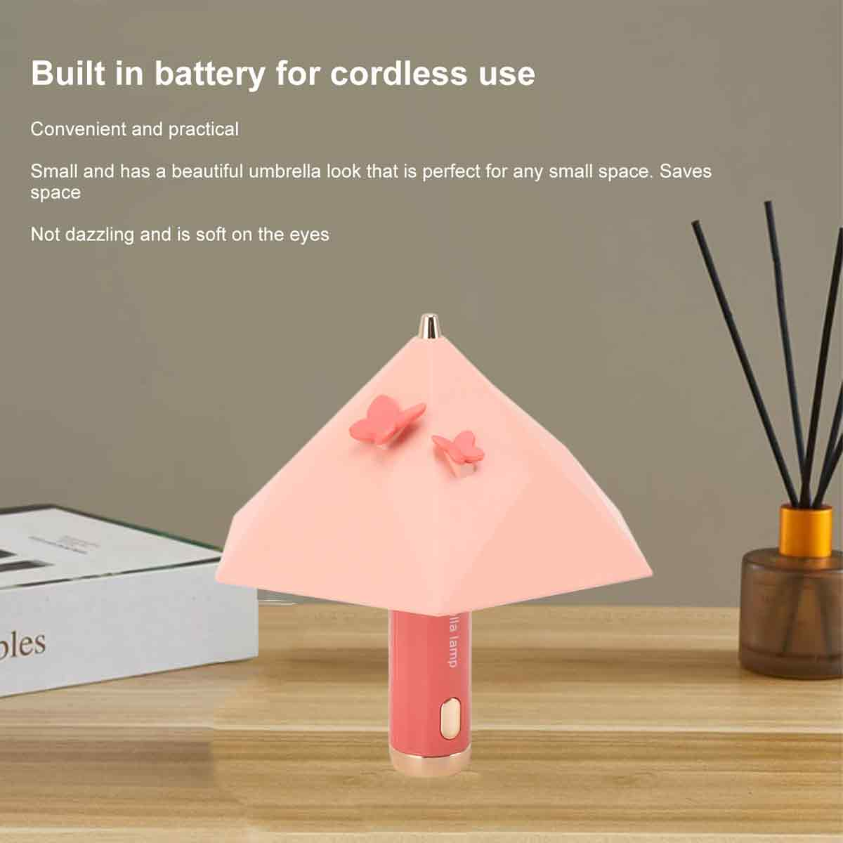 Eine kleine rosa Lampe in Schirmform mit zwei Schmetterlingen auf einer Tischoberfläche mit Werbetext oben.