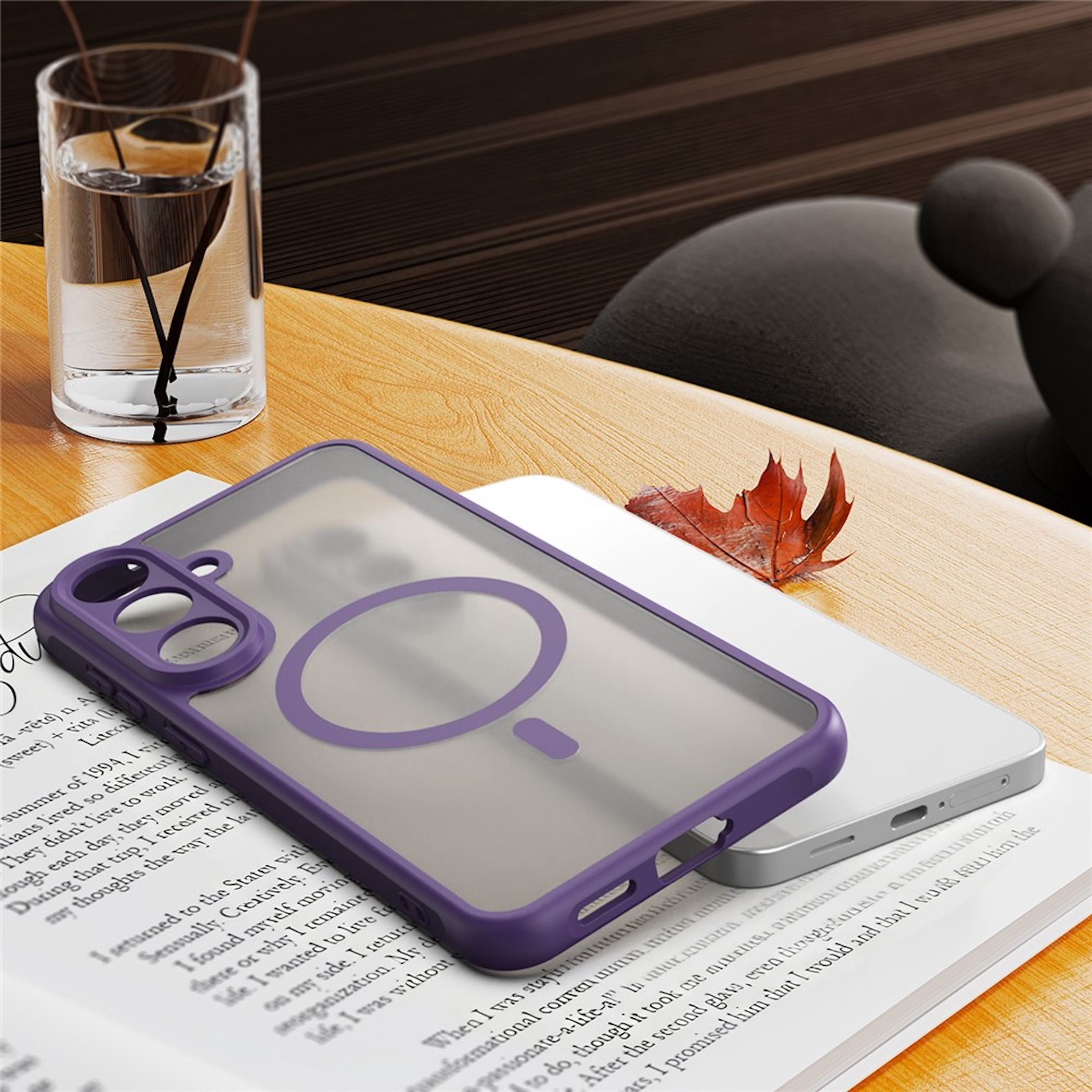 Eine lila Smartphone-Hülle liegt auf einem Buch auf einem Holztisch, daneben ein Glas Wasser und ein Ahornblatt.