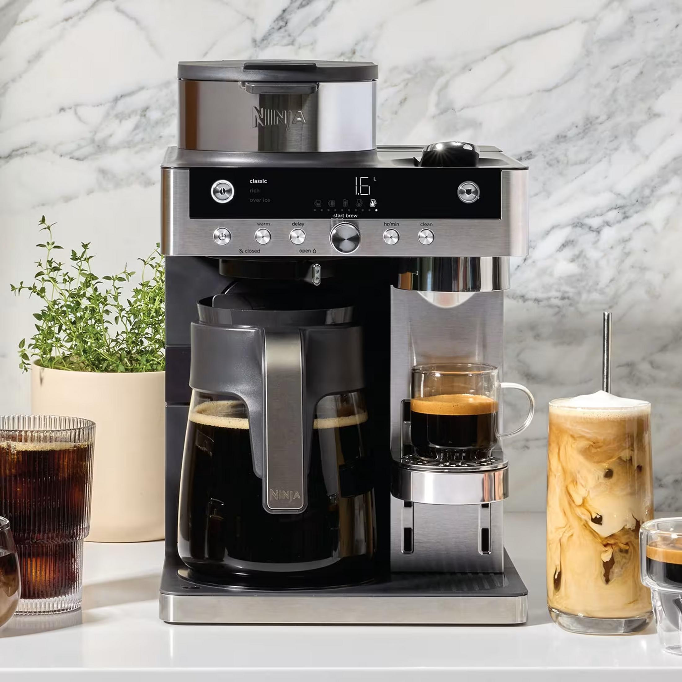 Moderna macchina da caffè con caraffa in vetro, espresso e caffè freddo in cucina con marmo.