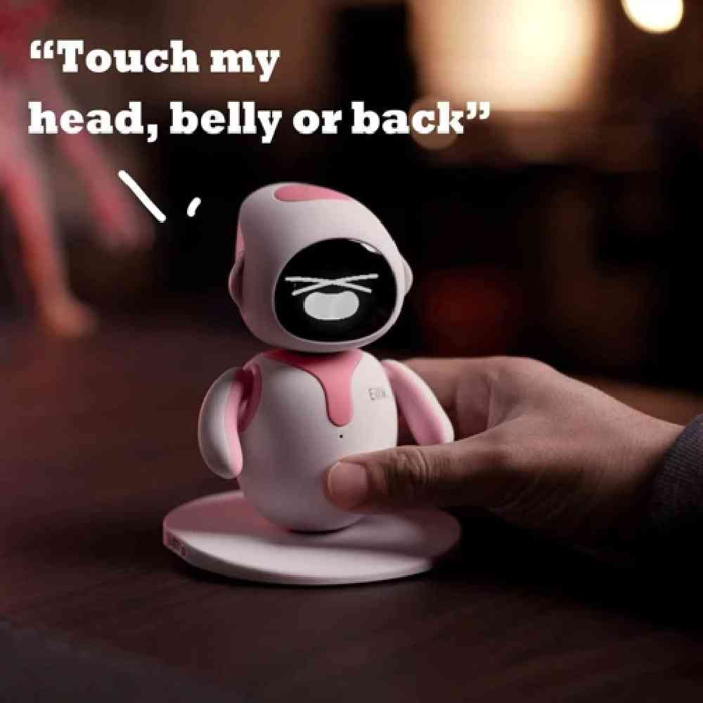 Yuvarlak tabanlı küçük beyaz ve pembe bir robot, bir el dokunuyor, üstte metin var.
