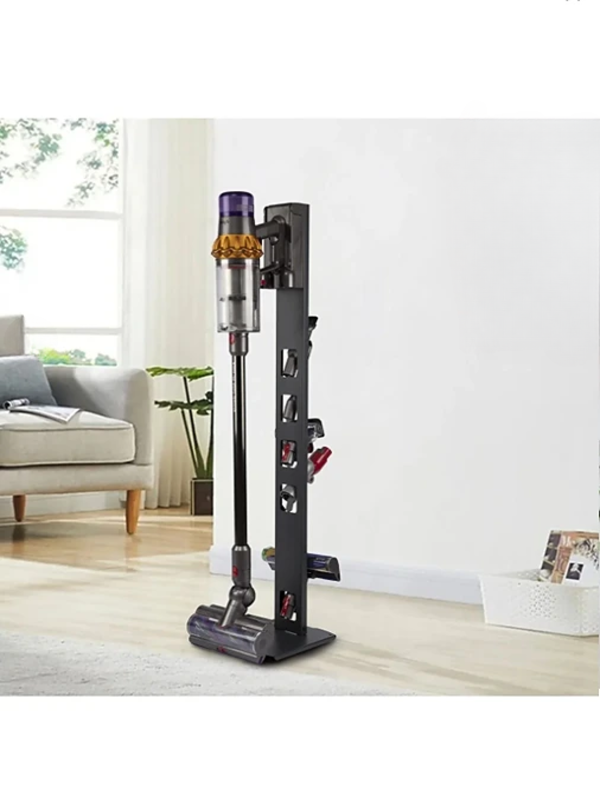 Aydınlık ve modern bir oturma odasında, siyah metal stand üzerinde duran kablosuz bir süpürge.