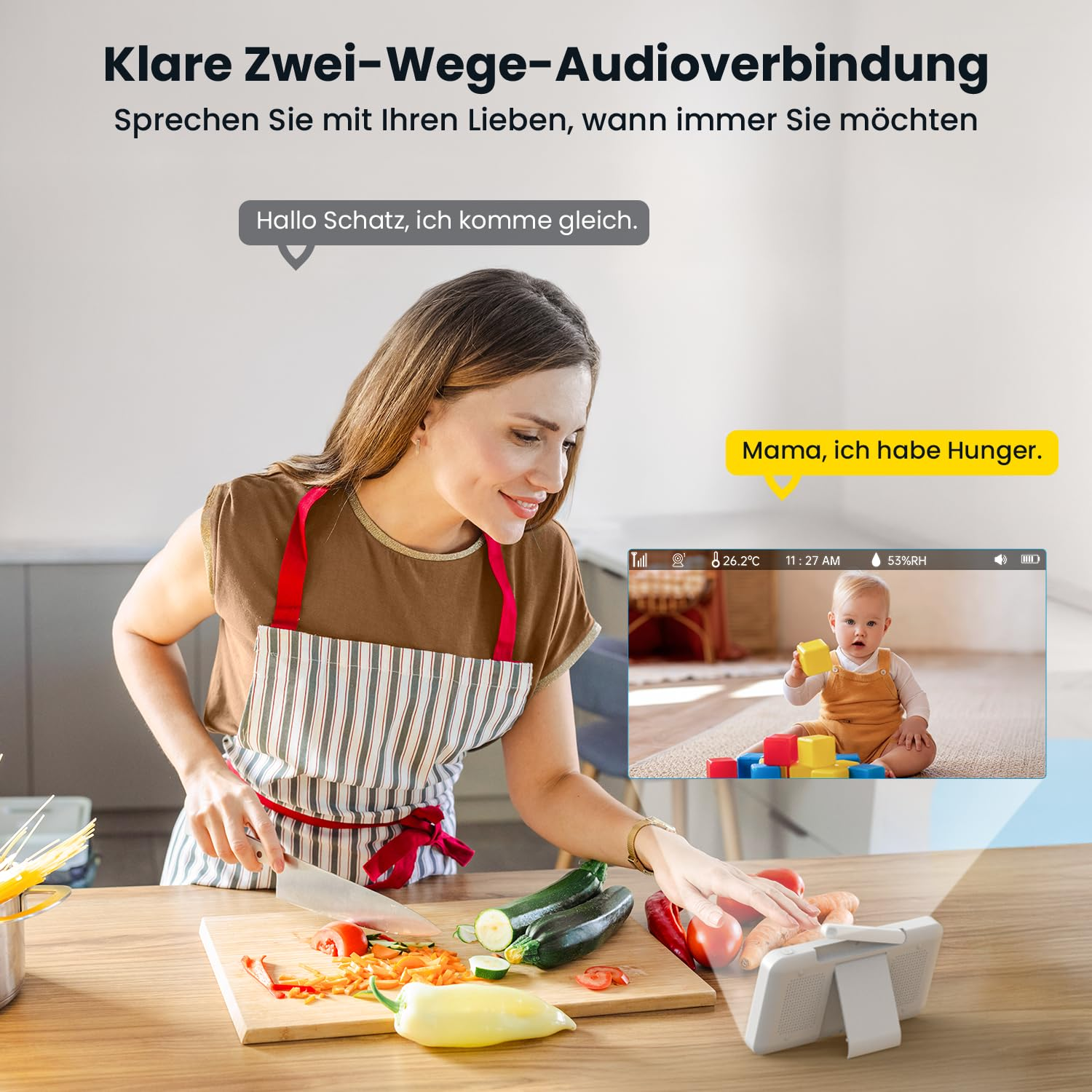 Une femme cuisine tout en surveillant son bébé sur un moniteur.