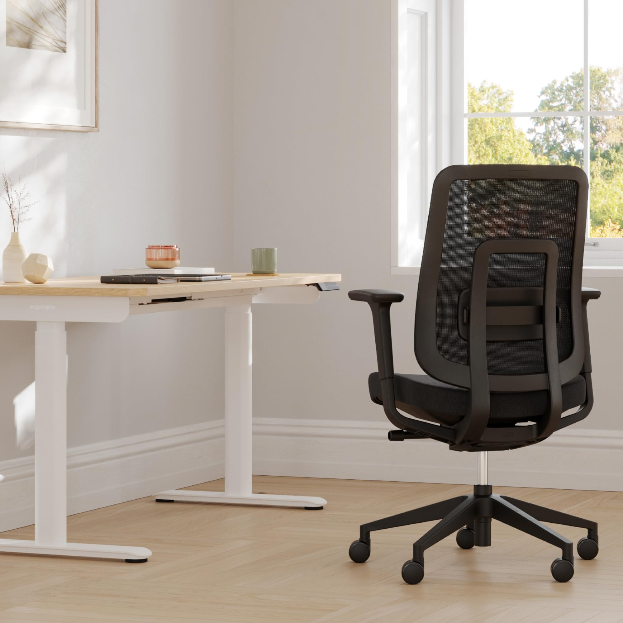 Une chaise de bureau noire se trouve devant un bureau en bois clair.