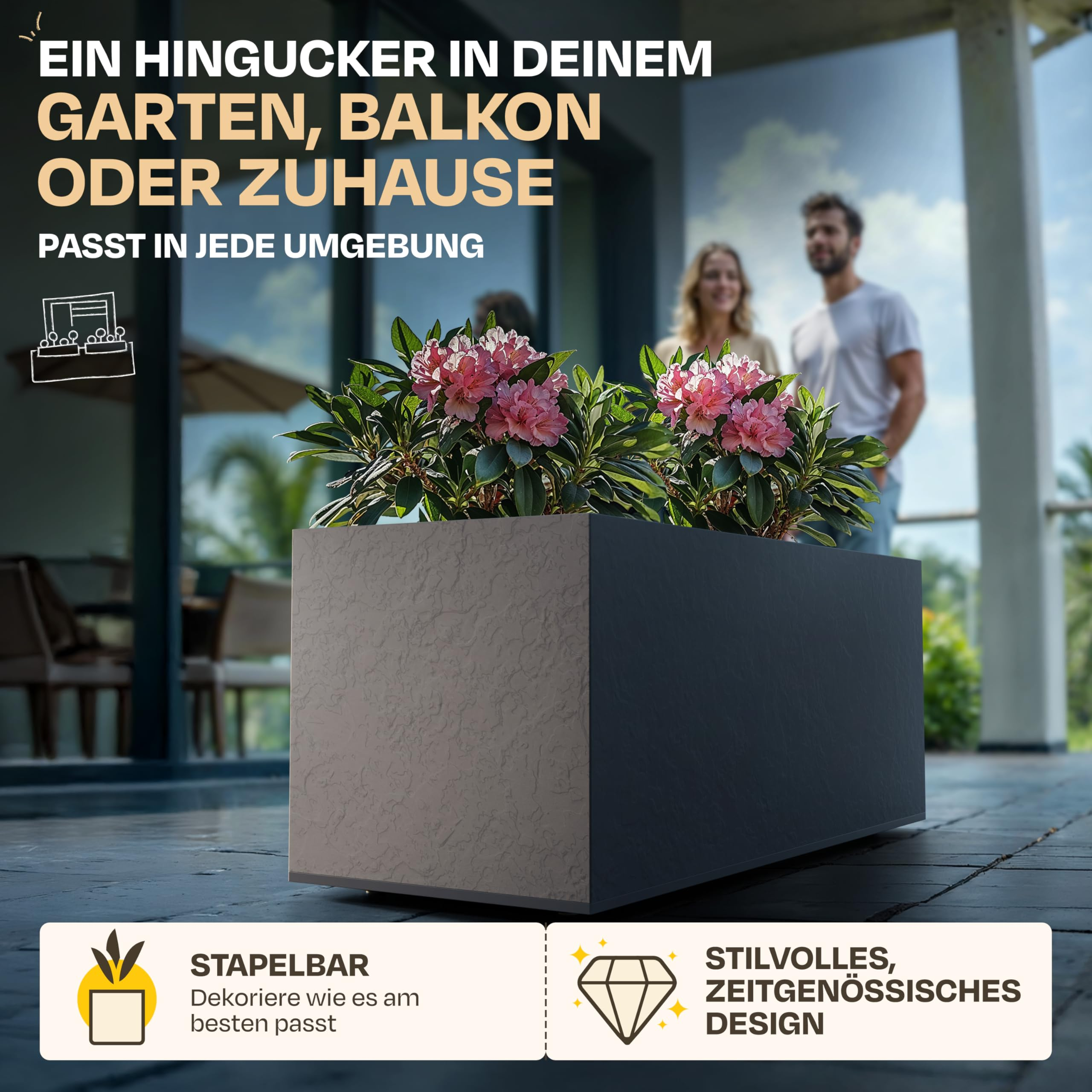 Une jardinière rectangulaire gris foncé avec des fleurs roses sur une terrasse, avec un couple souriant en arrière-plan.