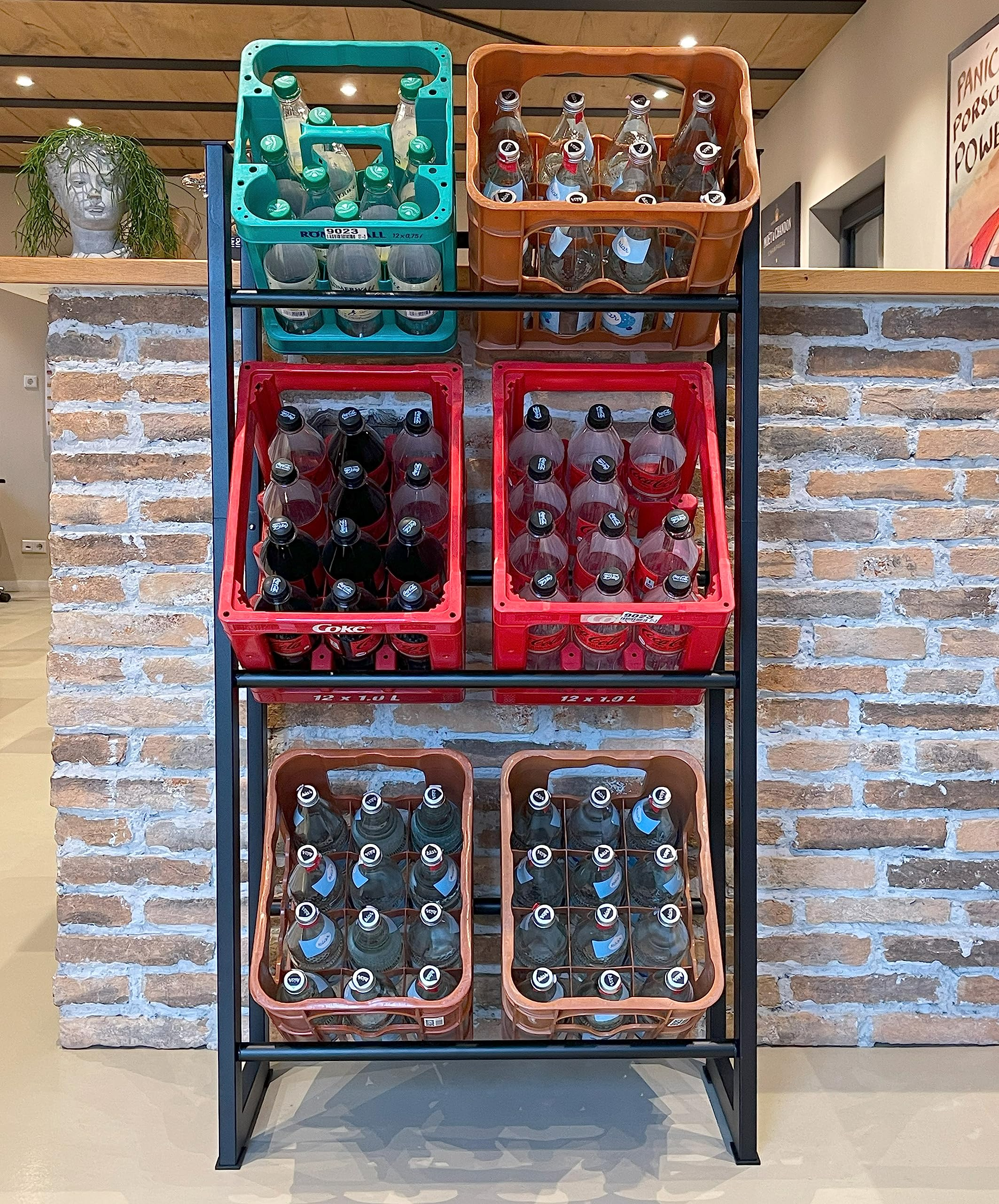 Ein Metallregal mit bunten Kunststoffkisten voller Glasflaschen steht vor einer Backsteinwand.