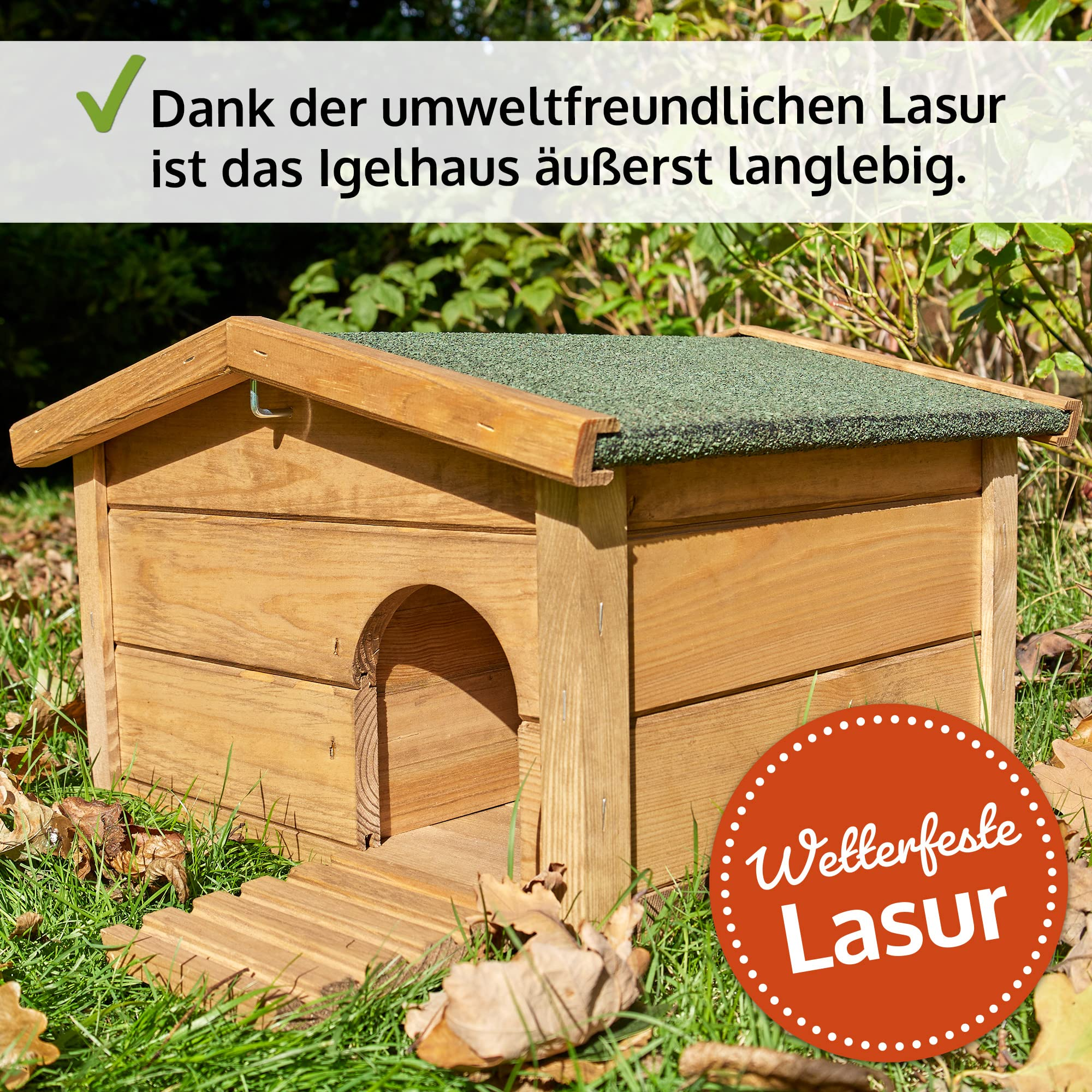 Une maison de hérisson en bois avec un toit vert sur la pelouse, entourée de feuilles et de buissons.