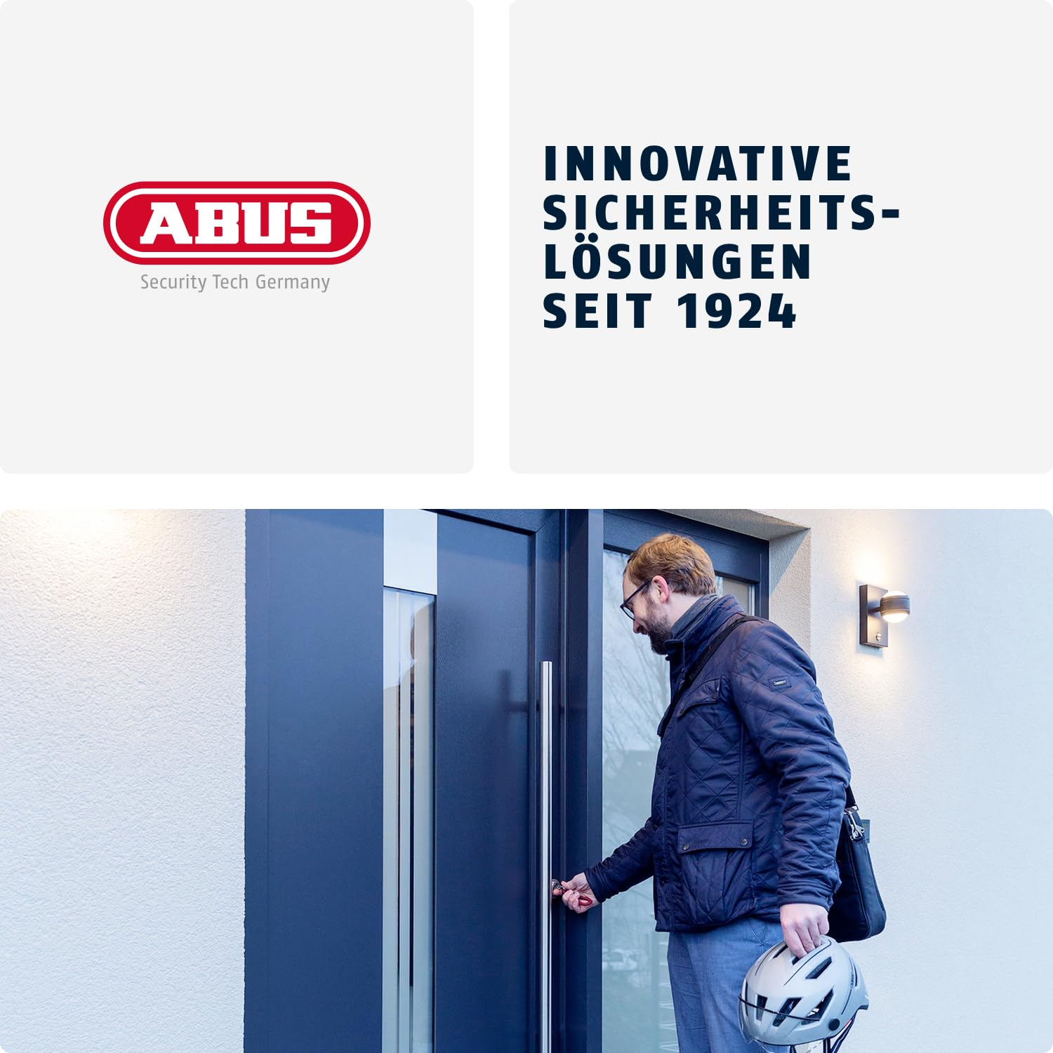 Ein Mann mit Helm öffnet eine schwarze Haustür; oben ist das rote Abus-Logo und Text zu sehen.