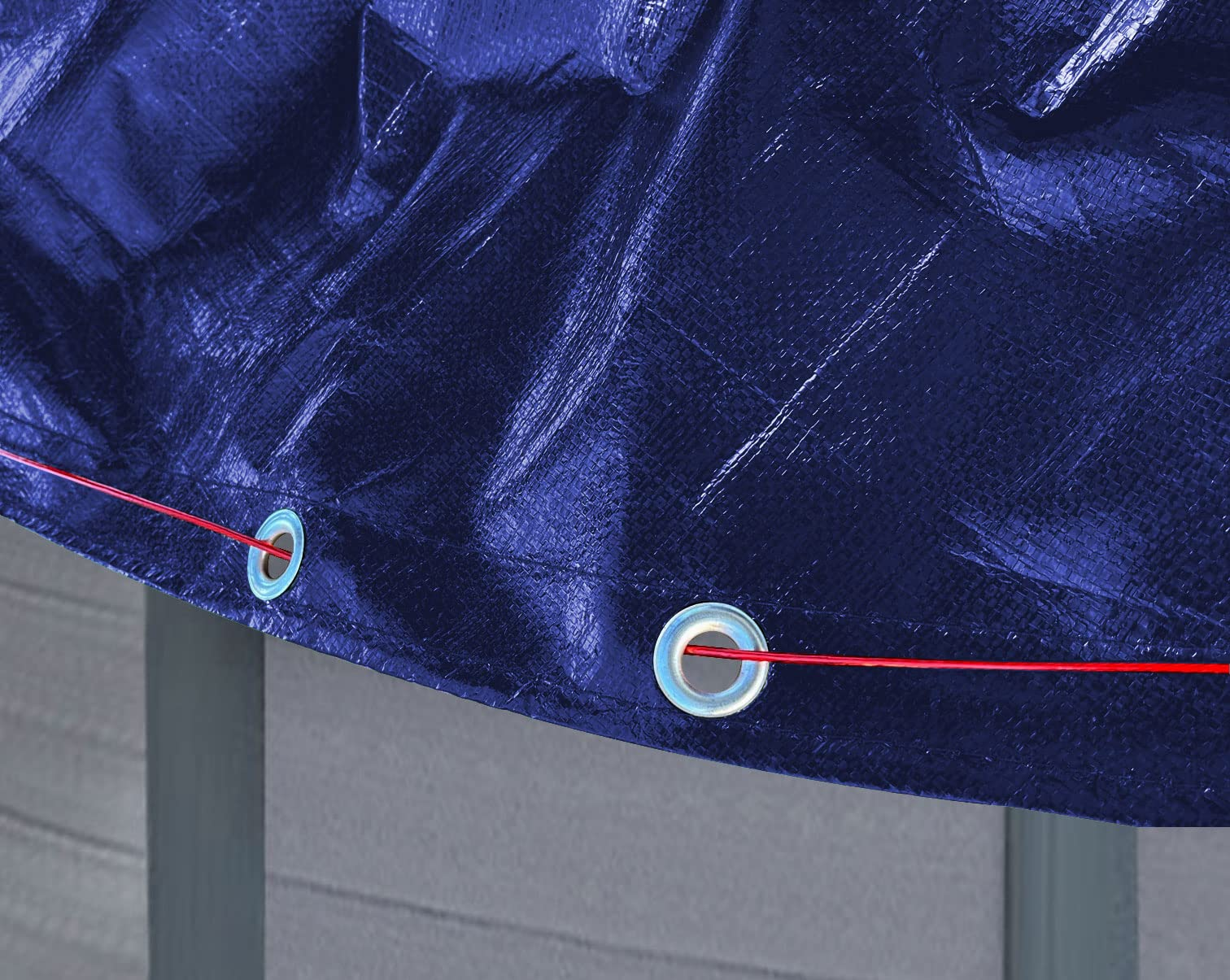 Une bâche en plastique bleu fixée par une corde rouge passée dans des œillets métalliques.