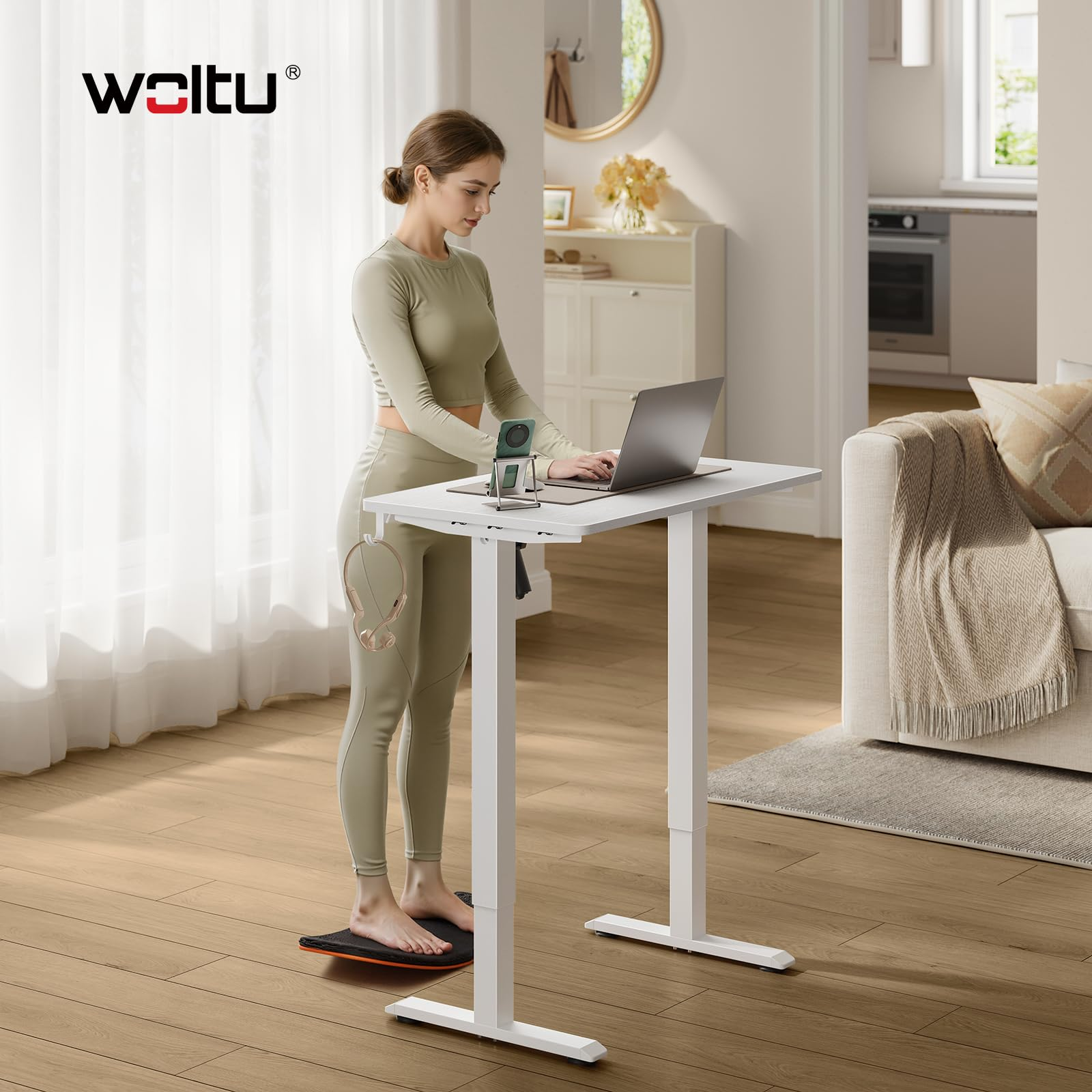 Une femme travaille sur un bureau debout blanc réglable en hauteur sur une planche d'équilibre.
