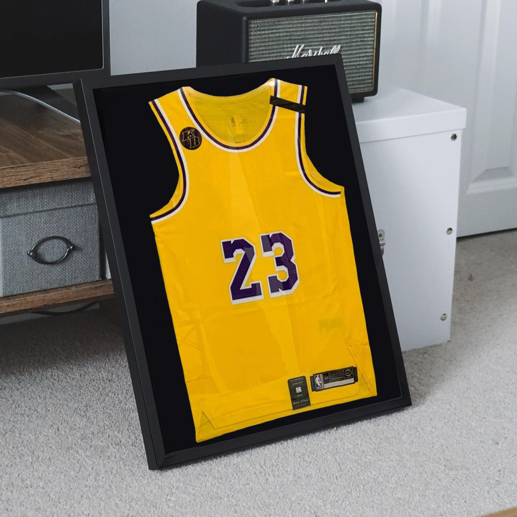 Ein gelbes Basketballtrikot mit der Nummer 23 ist in einem schwarzen Rahmen an einer Wand befestigt.