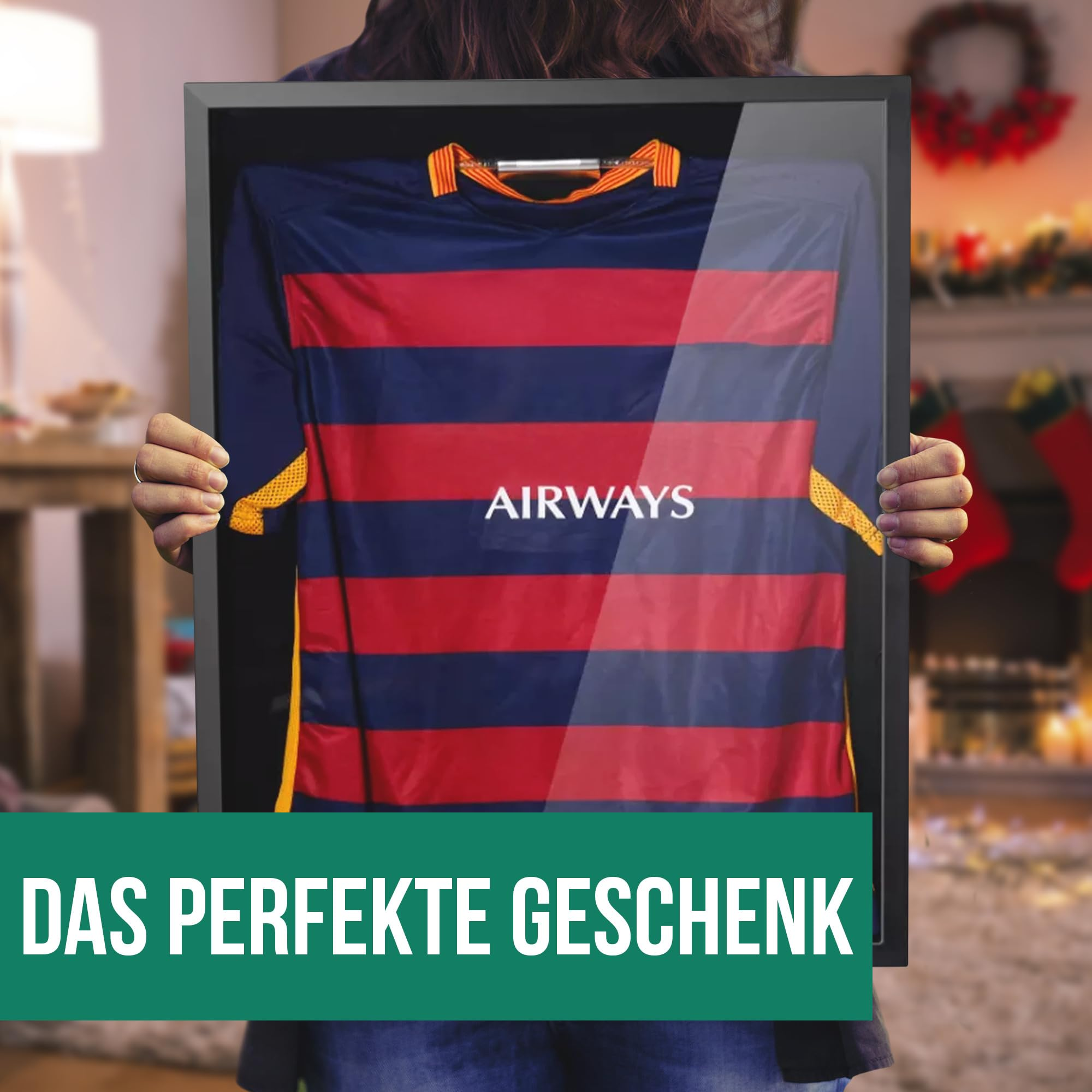 Person hält gerahmtes rot-blaues Fußballtrikot mit der Aufschrift AIRWAYS in einem gemütlichen Raum.