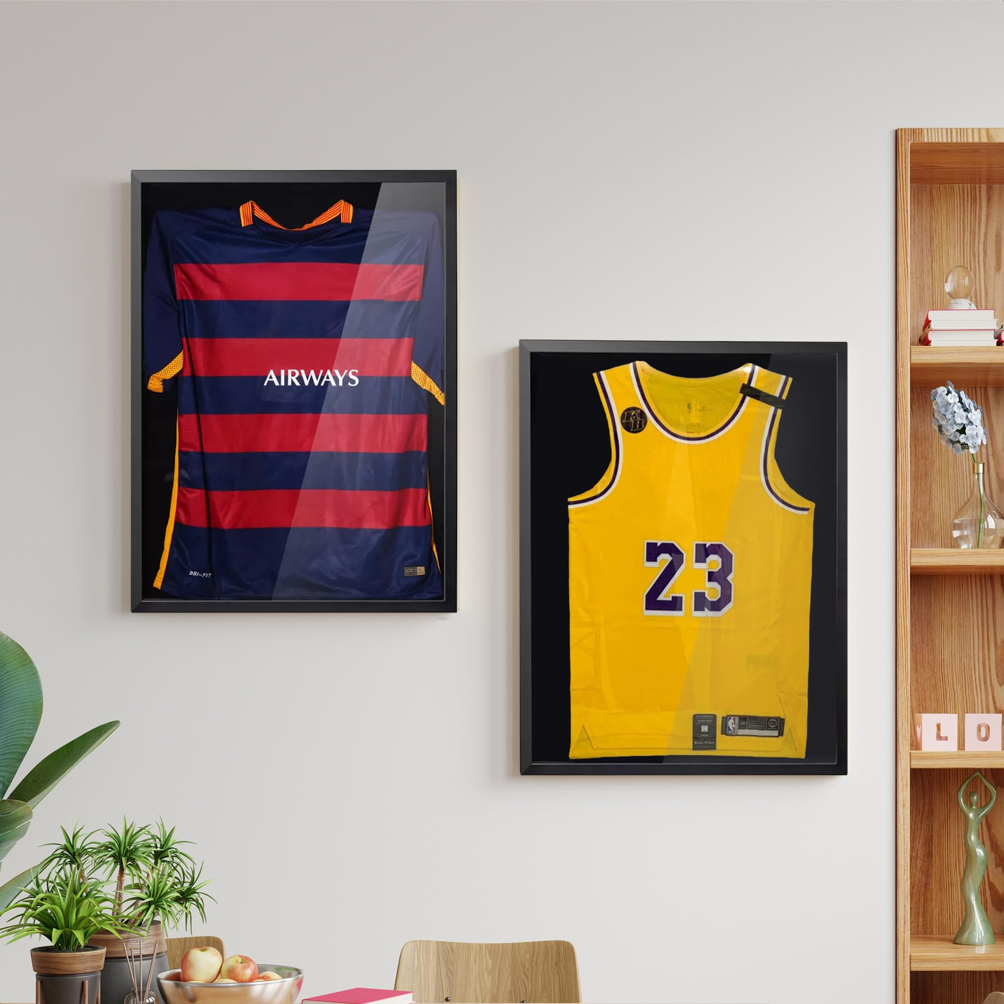 Zwei gerahmte Trikots an einer Wand: links ein blau-rotes Fußballtrikot, rechts ein gelbes Basketballtrikot mit der Nummer 23.