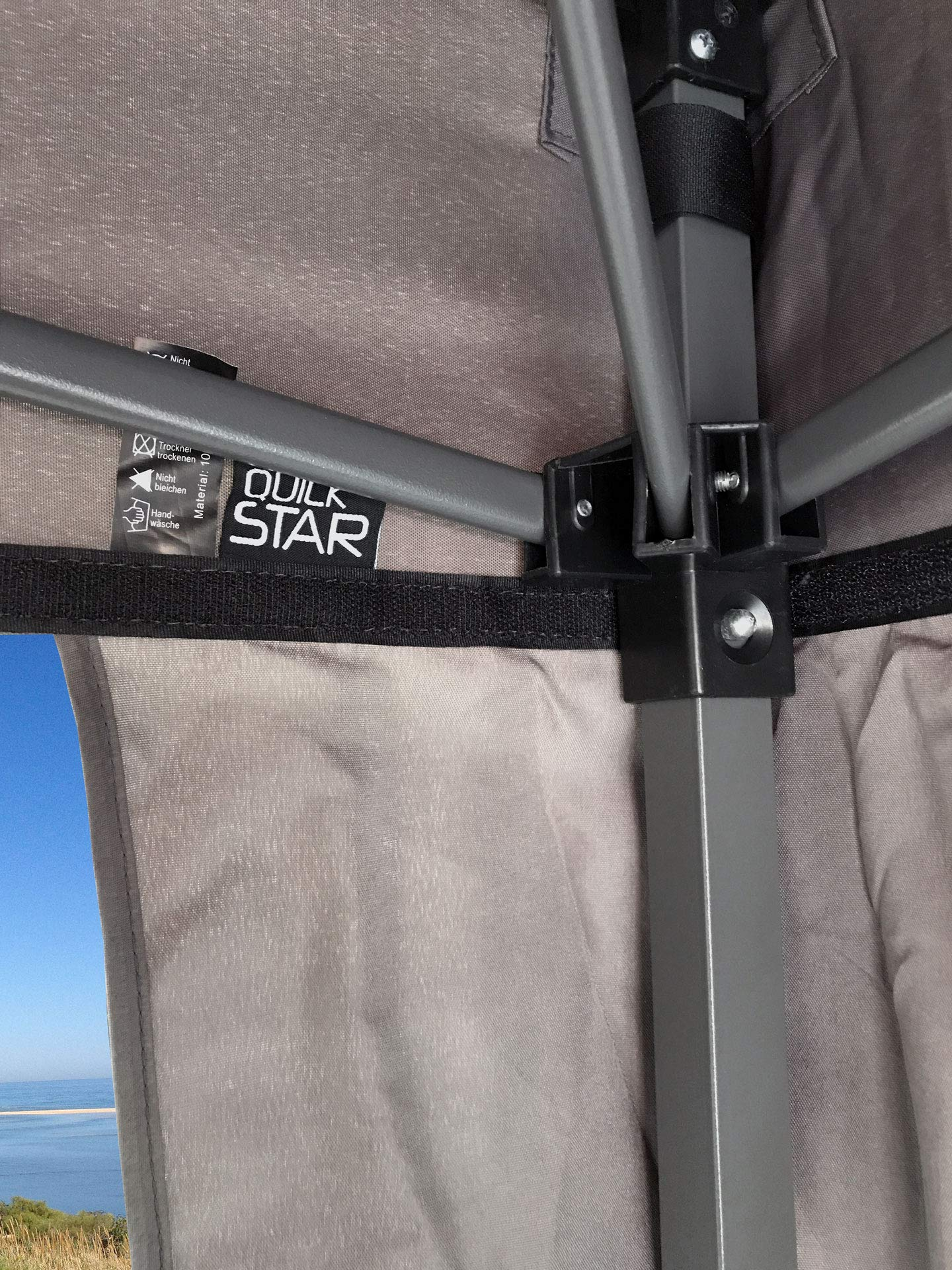 Vue détaillée d'une armature de tente grise avec logo Quick Star, étiquette et vue sur la mer.