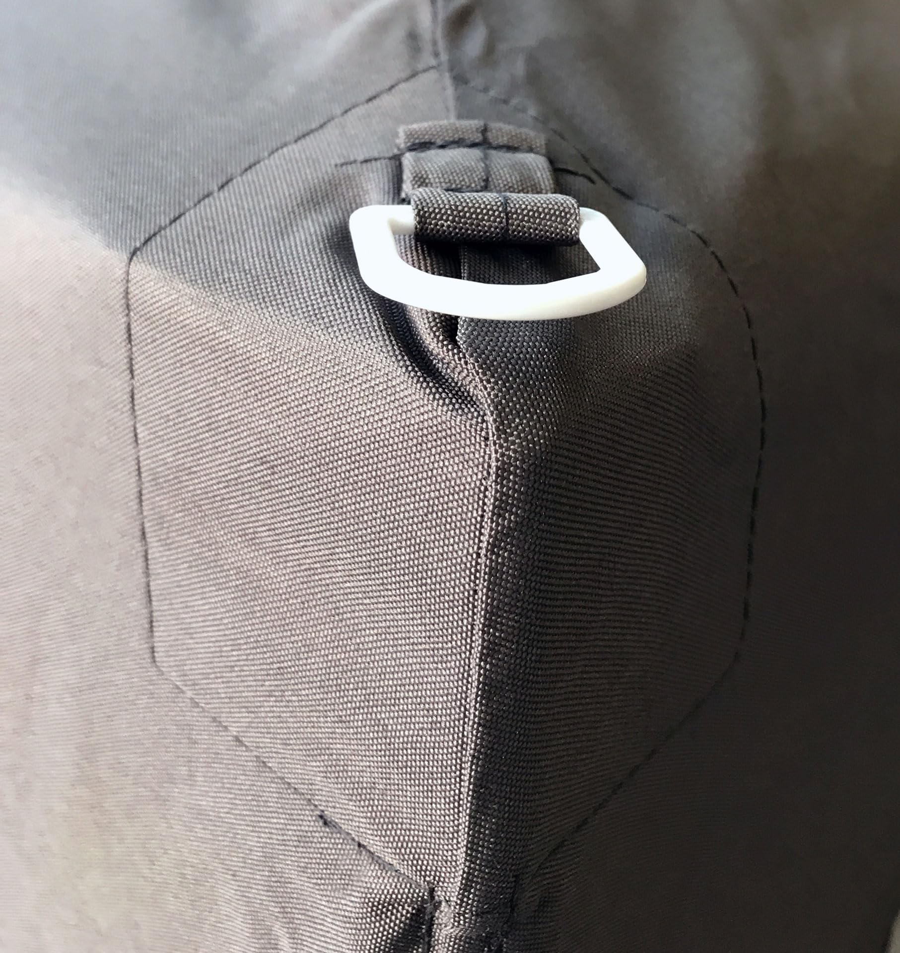 Tissu gris avec un coin renforcé et une boucle en plastique blanc.