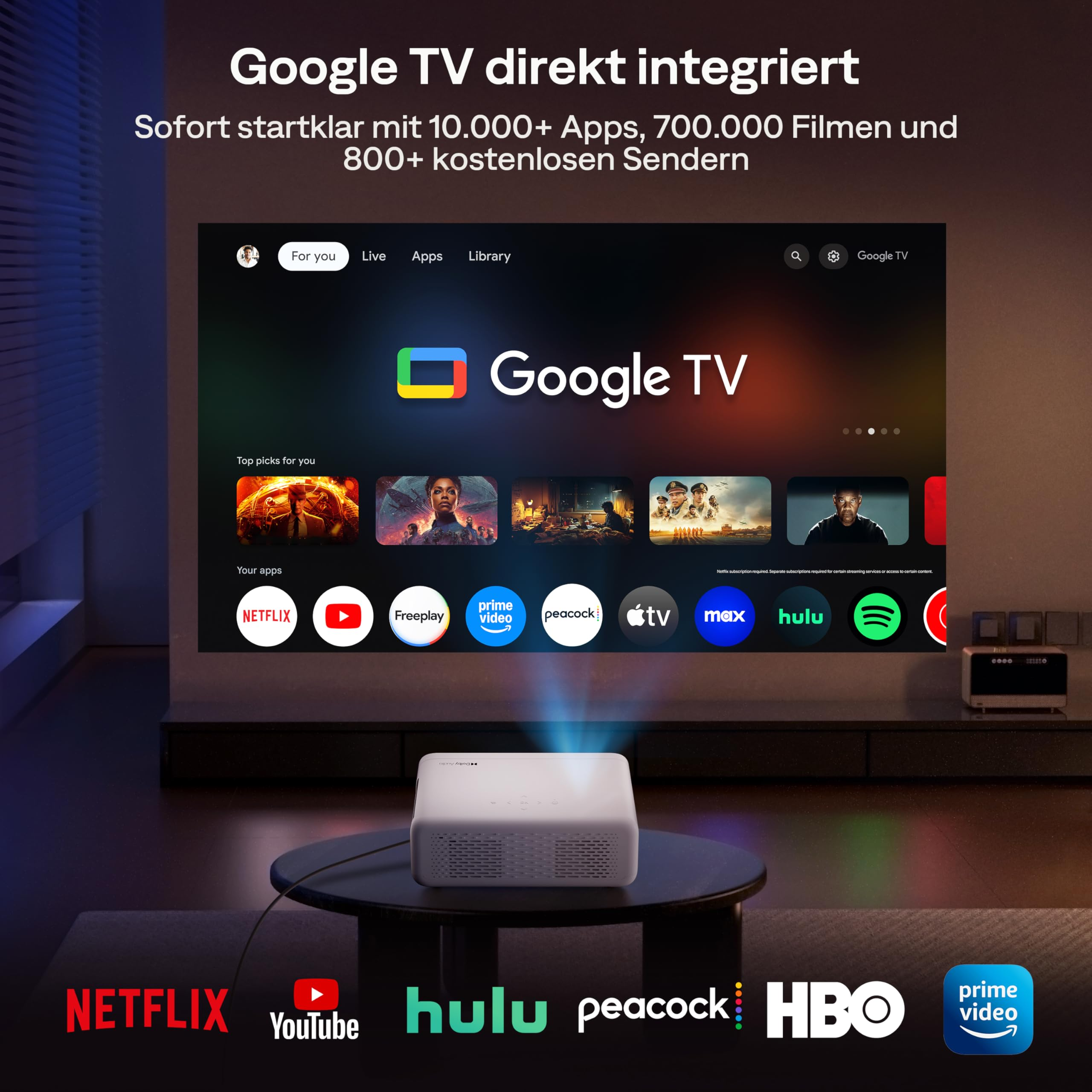 Un proiettore bianco su un tavolo proietta l'interfaccia Google TV sulla parete.