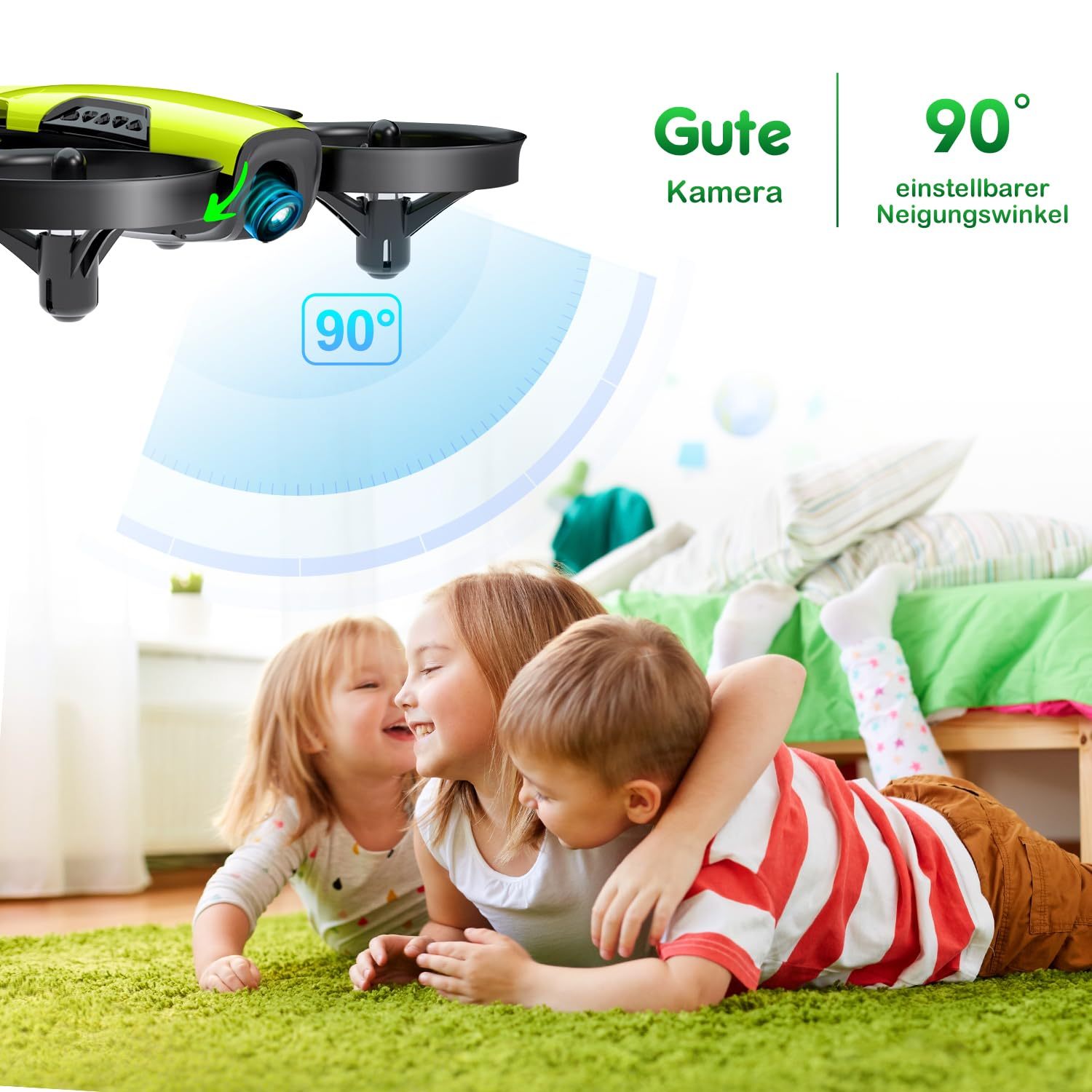 Tre bambini felici giacciono su un tappeto verde mentre un drone con telecamera a 90 gradi fluttua sopra di loro.