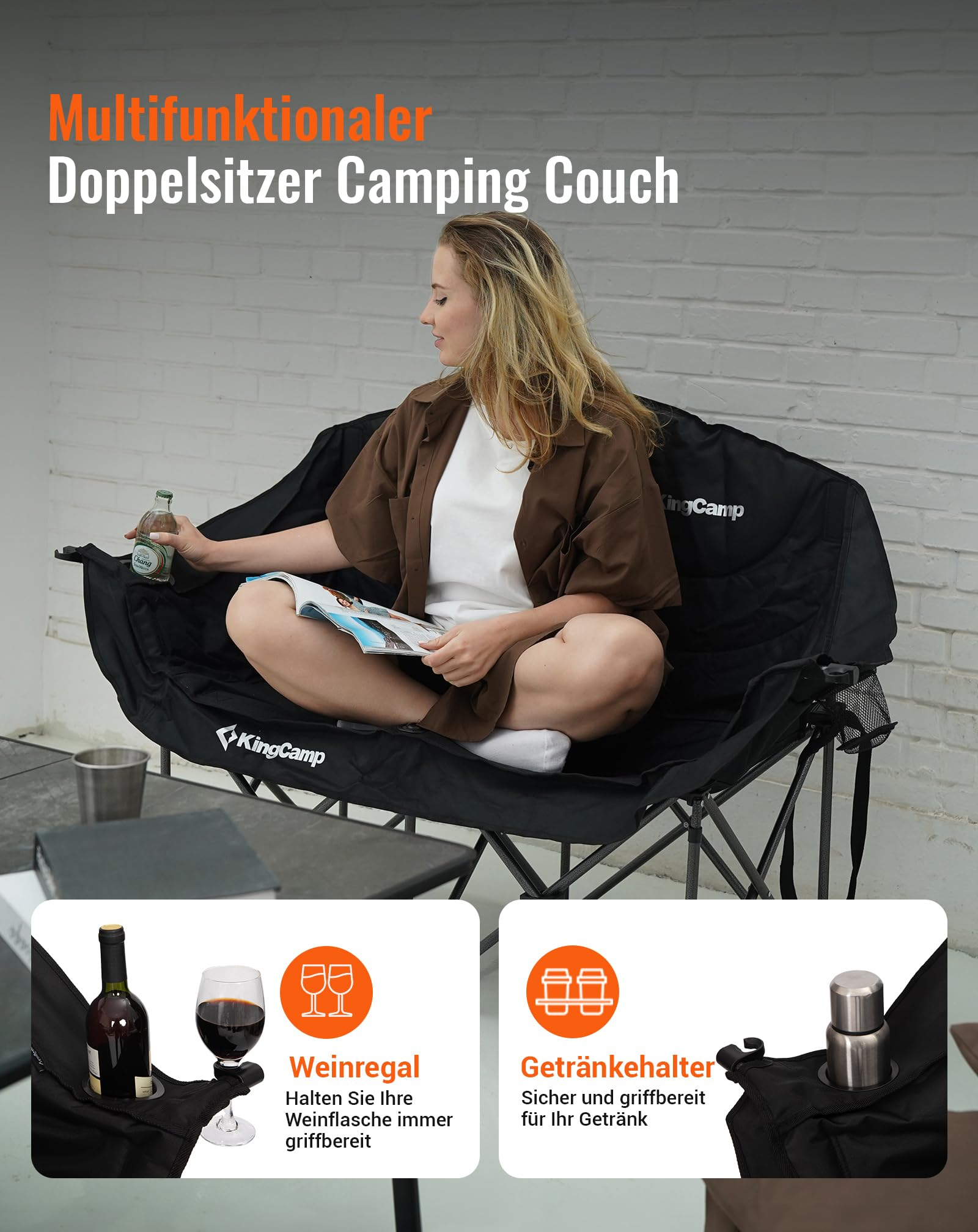Eine Frau sitzt auf einer schwarzen KingCamp-Doppelcampingcouch, liest und hält ein Getränk, mit Insets für Flaschenhalter.