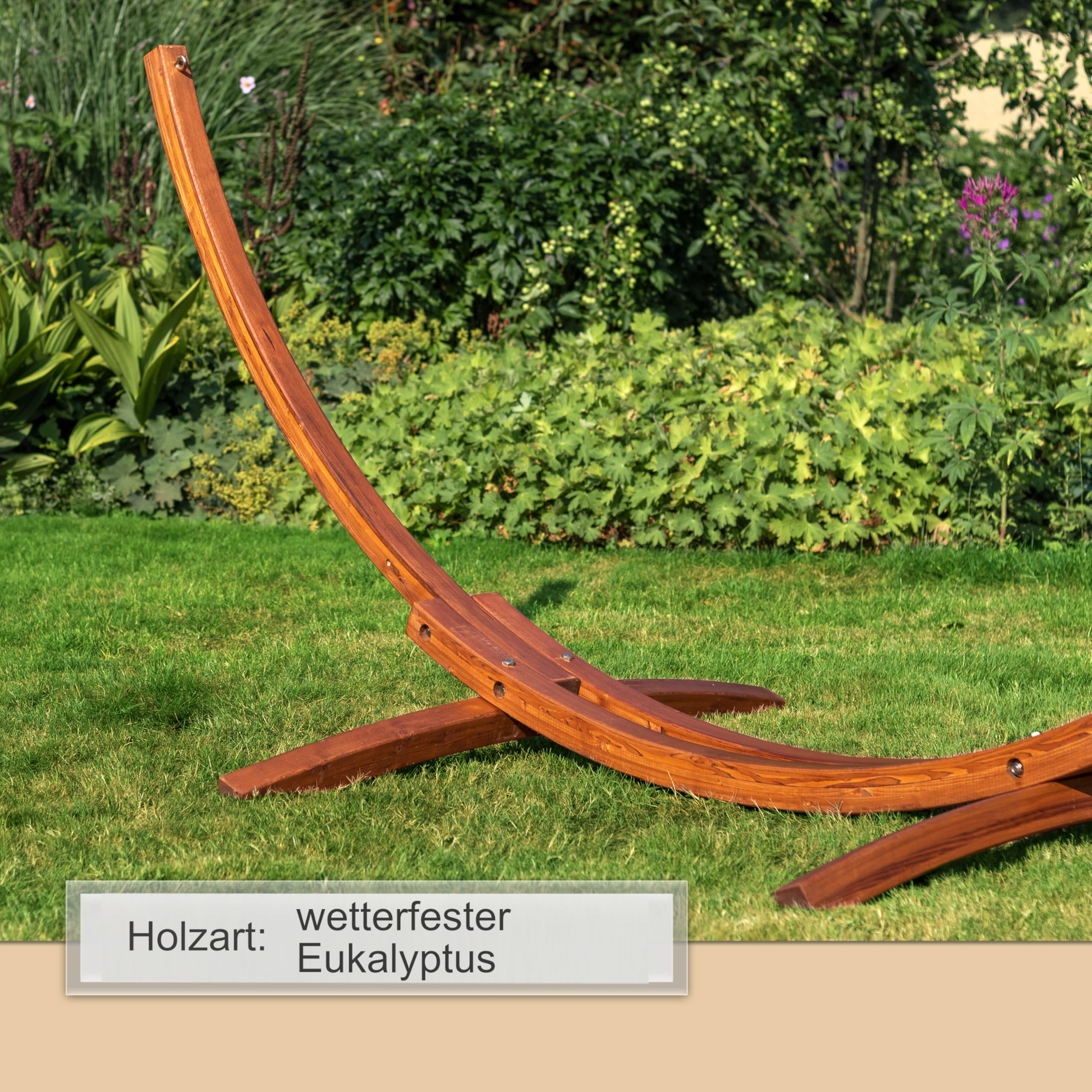 Ein Holz-Hängemattenständer aus wetterfestem Eukalyptus steht auf grünem Gras in einem üppigen Garten.