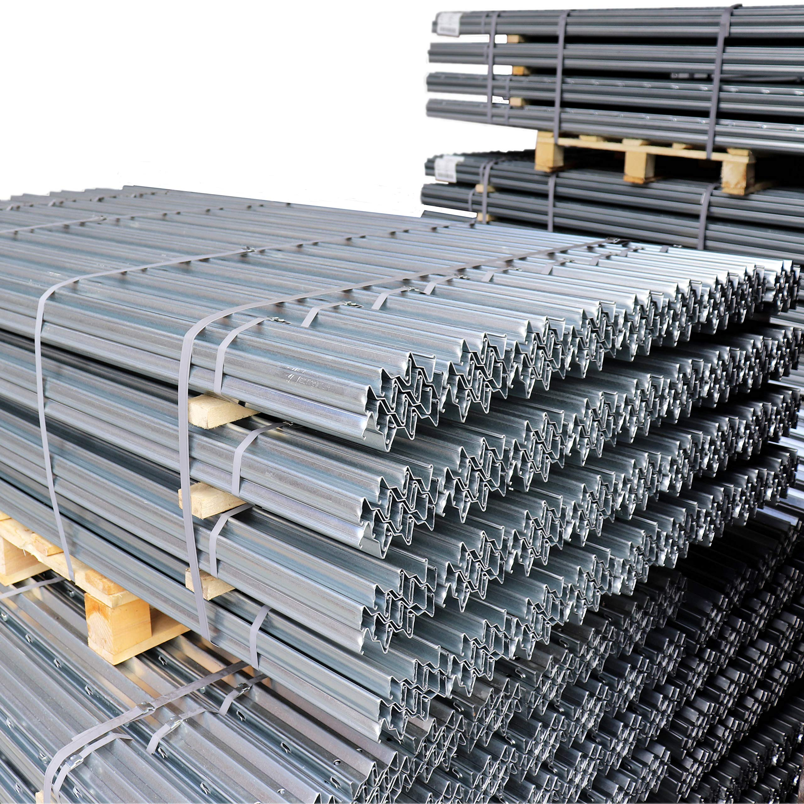 Fasci di profili metallici grigi impilati ordinatamente su pallet di legno su sfondo bianco.