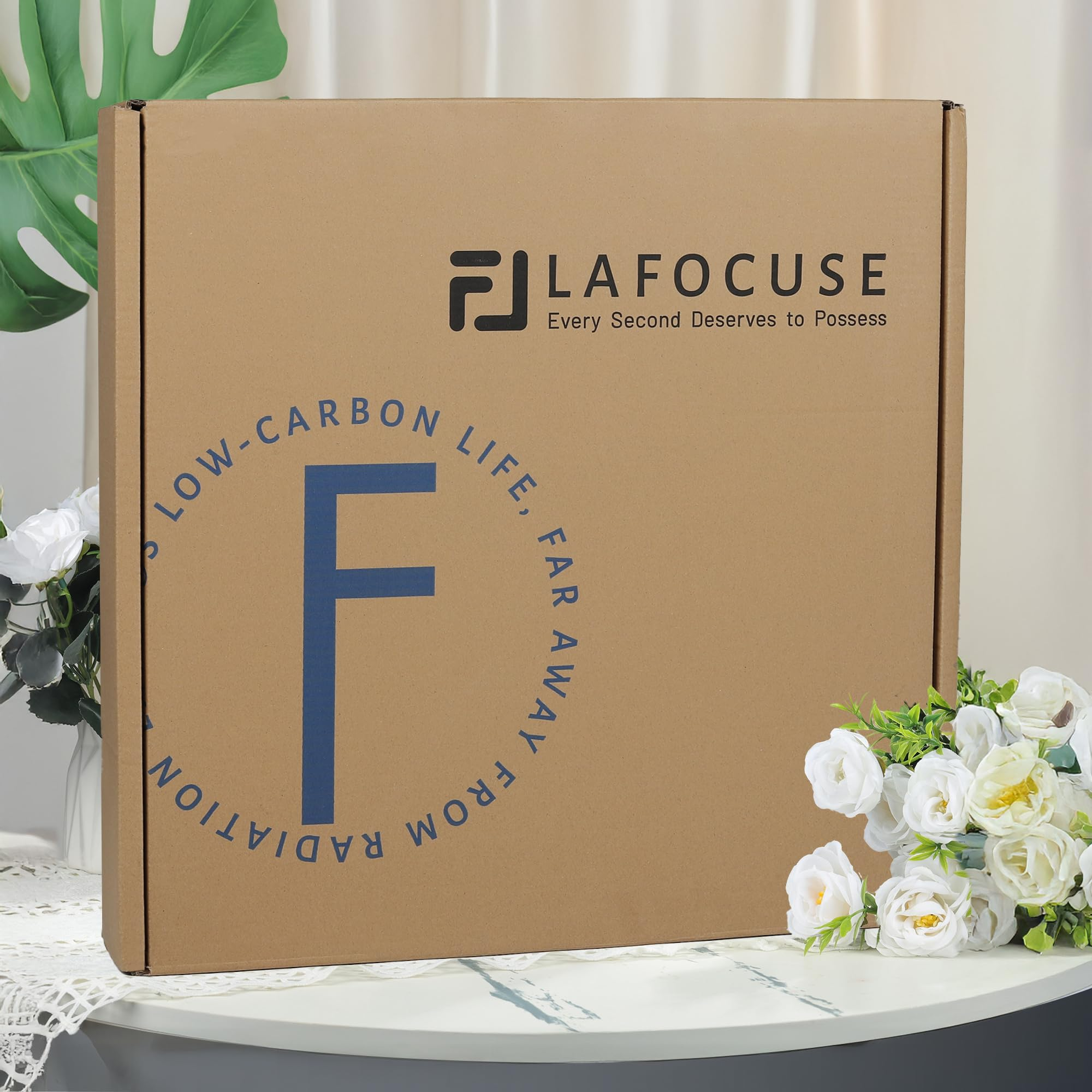 Une boîte en carton marron avec le texte LAFOCUSE se trouve sur une table, entourée de fleurs blanches.