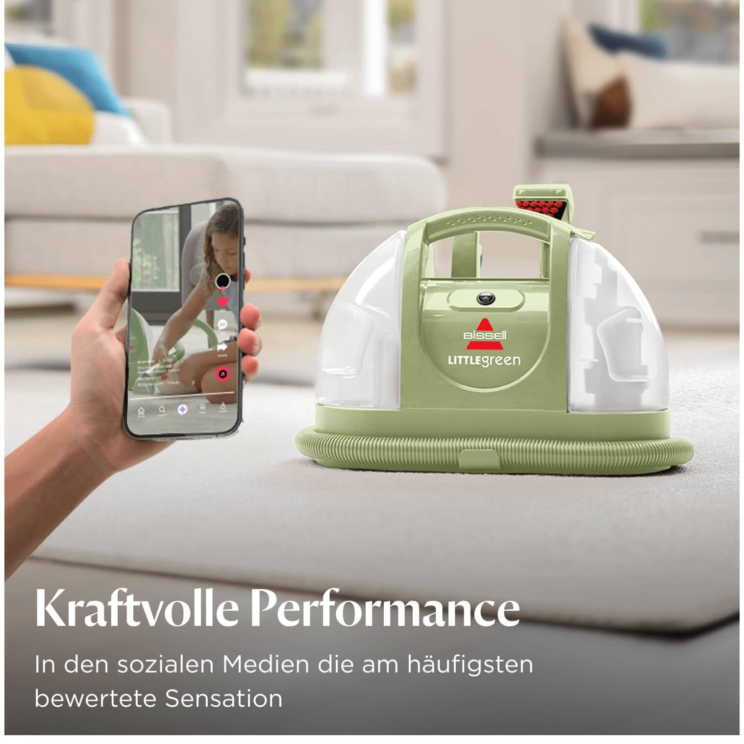 Un pulitore per tappeti verde Bissell Little Green si trova sul pavimento vicino a uno smartphone.