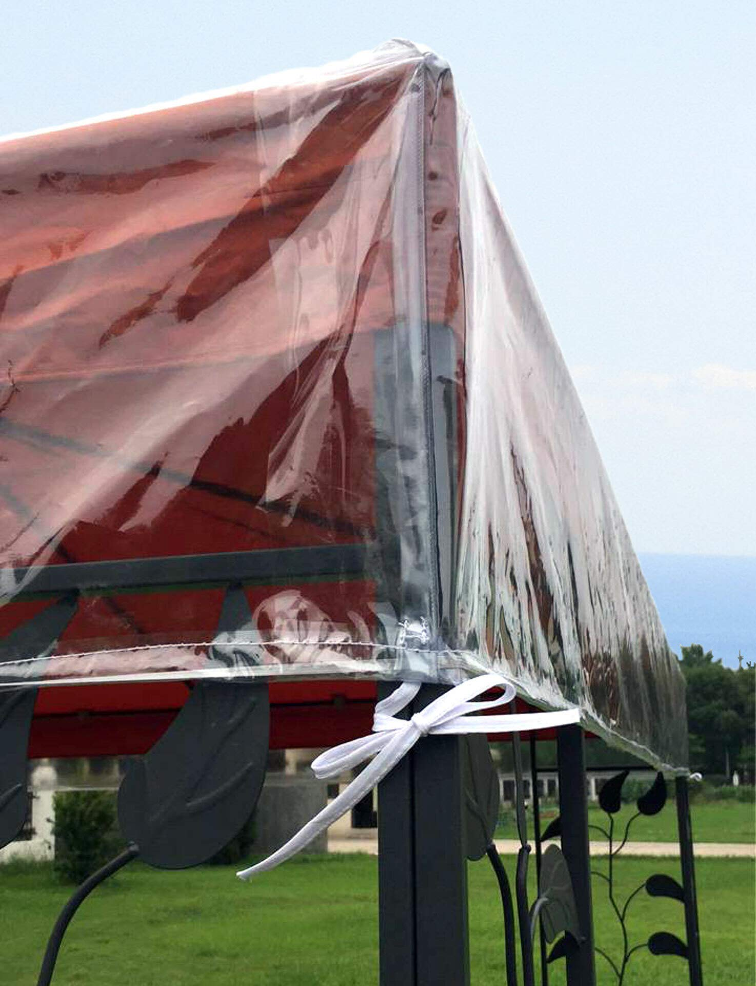 Ein Pavillon mit einer roten Haube ist mit einer transparenten Schutzplane bedeckt, die mit weißen Bändern befestigt ist.
