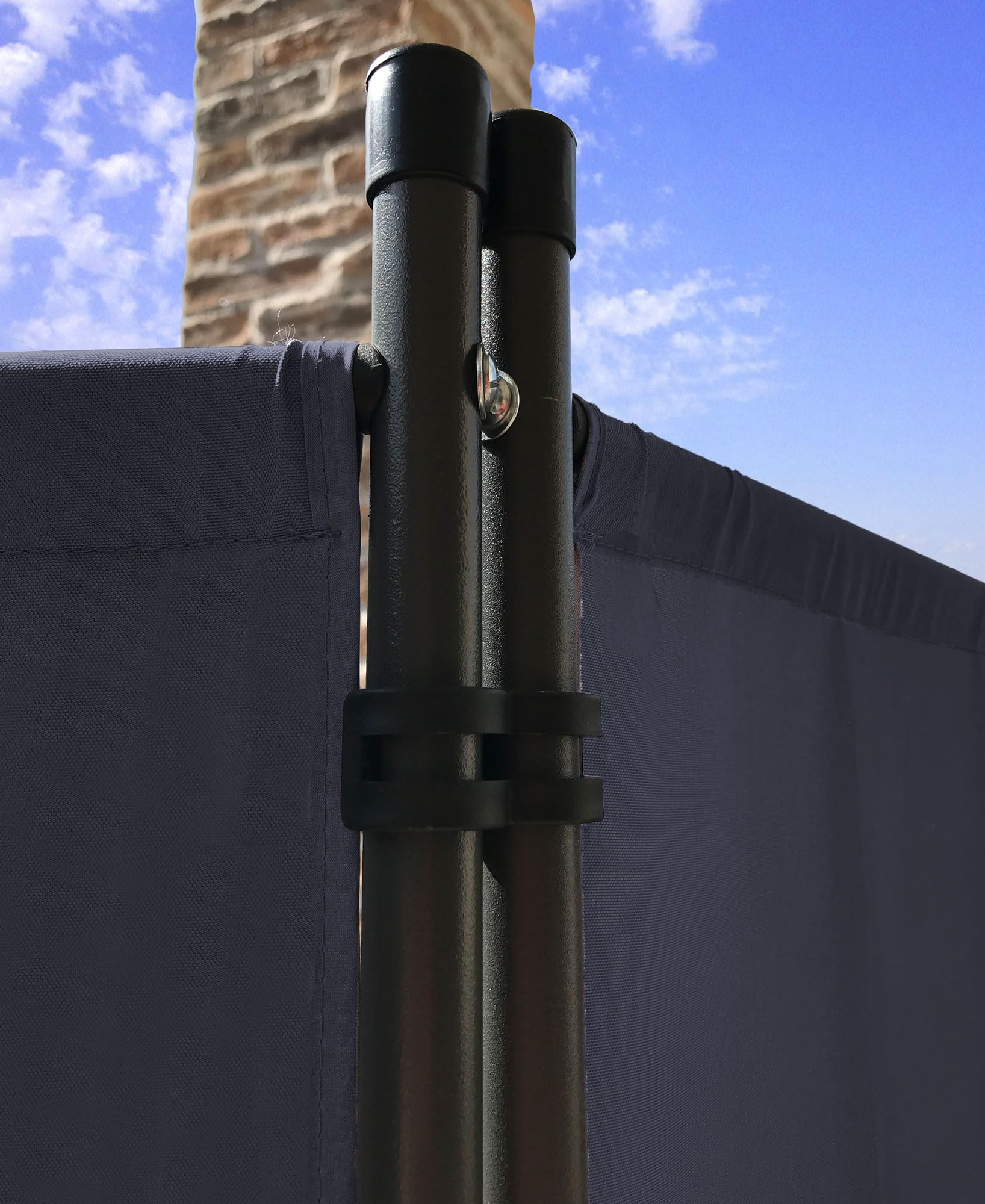 Zwei schwarze Metallstangen halten einen blauen Sichtschutz vor einem blauen Himmel.