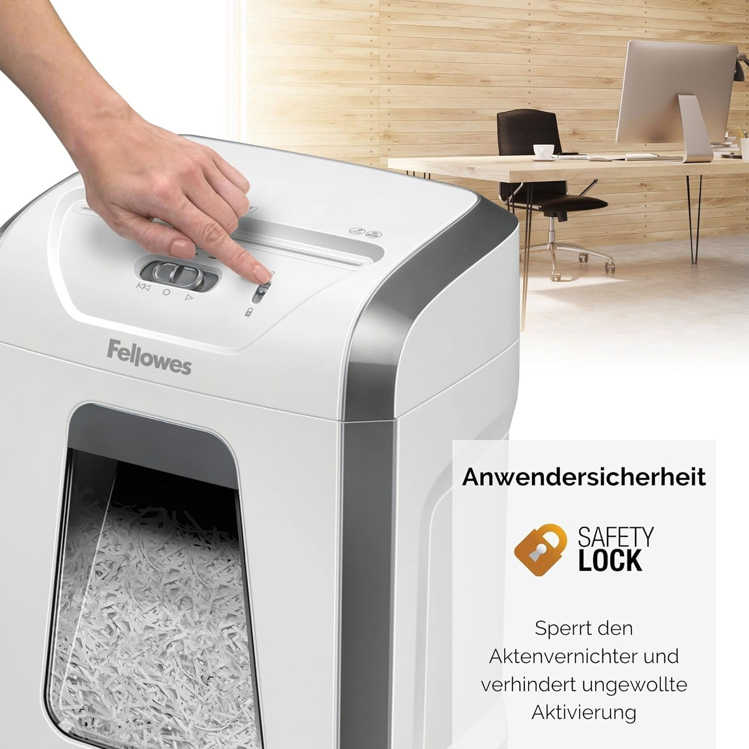 Eine Hand drückt die Sicherheitssperre auf einem weißen Fellowes Aktenvernichter in einem Büro.