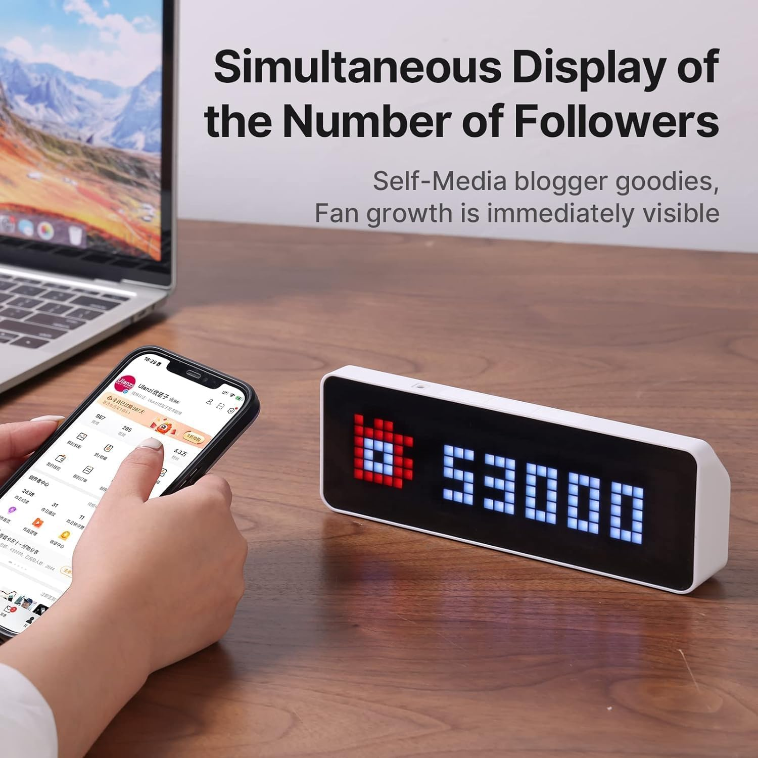 Un display LED digitale su una scrivania mostra il numero 53000 accanto a uno smartphone con profilo social.