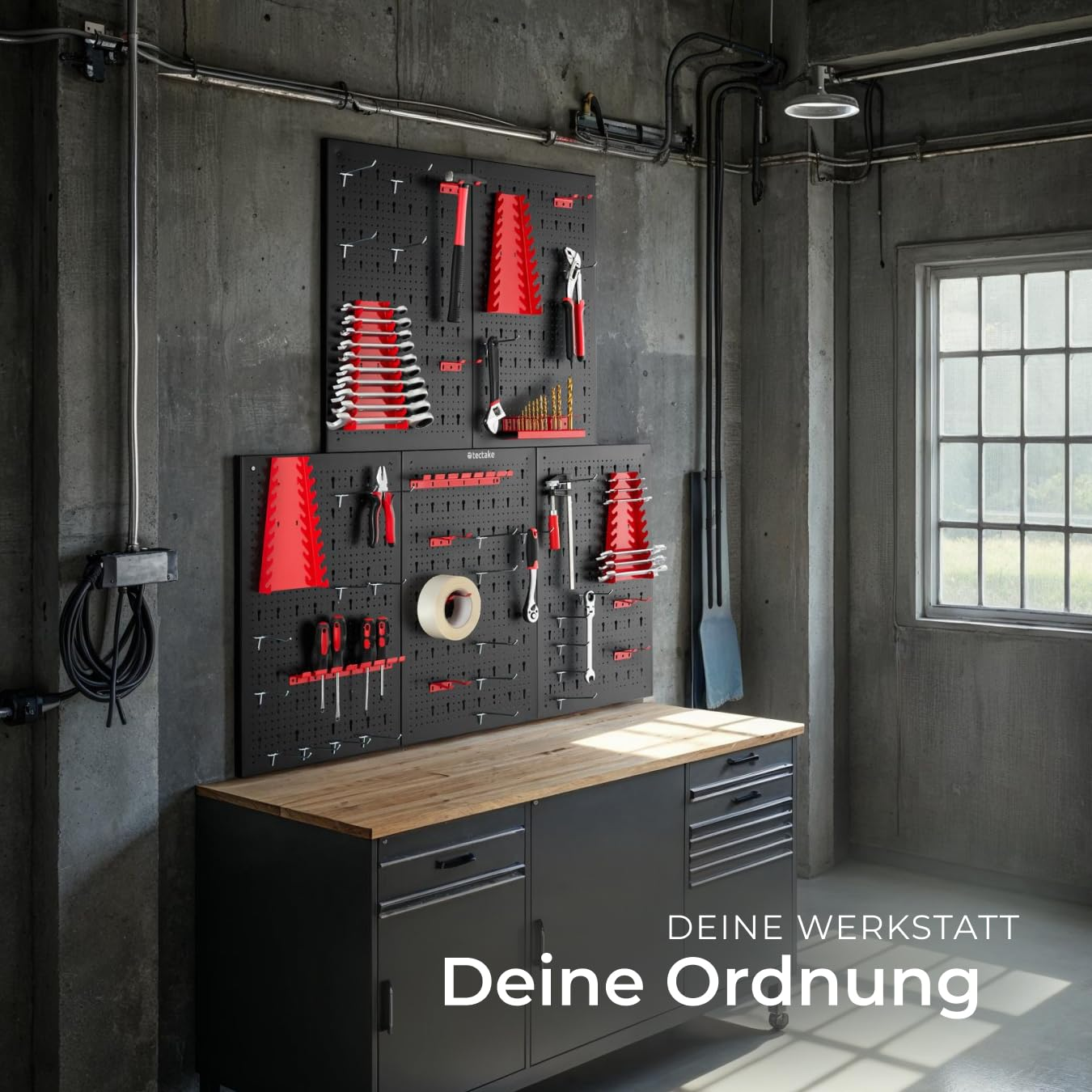 Werkstattwand mit geordneten roten und schwarzen Werkzeugen über einer Werkbank an einer Betonwand.