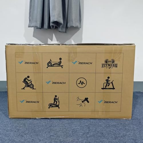 Ein großer brauner Karton mit Fitnessgerät-Symbolen steht auf blauem Teppich vor einer Wand.