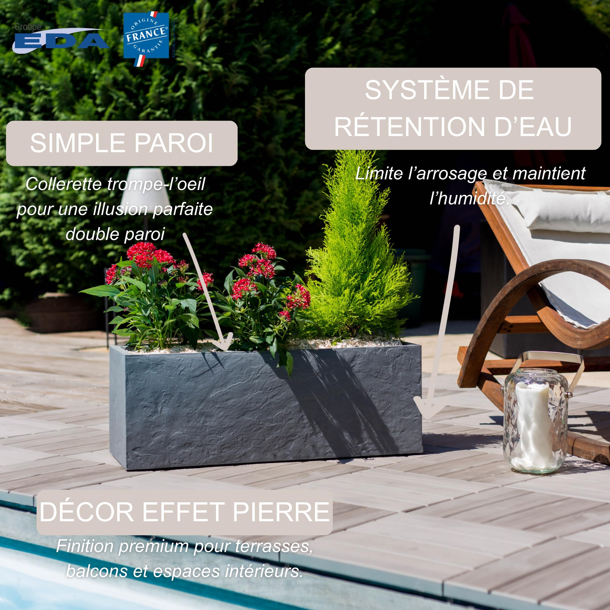 Jardinière grise effet pierre avec fleurs rouges et arbuste vert sur terrasse en bois.