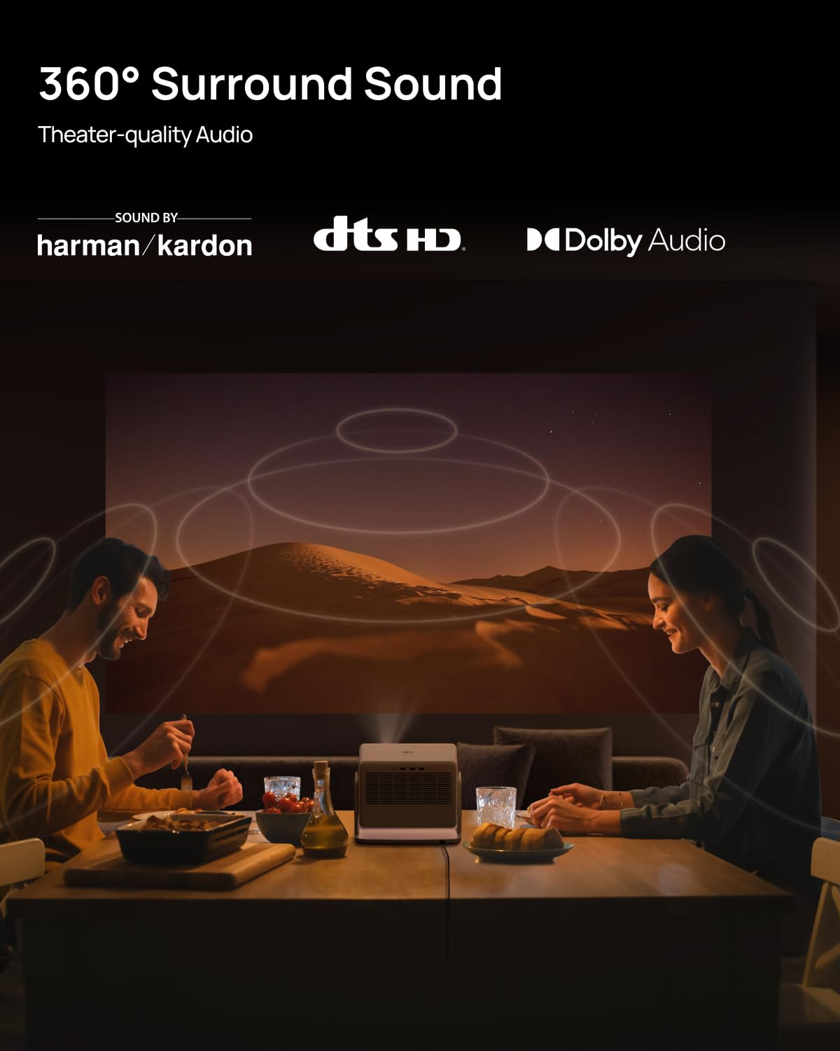 Una coppia cena mentre un proiettore mostra un deserto, con loghi audio surround in alto.