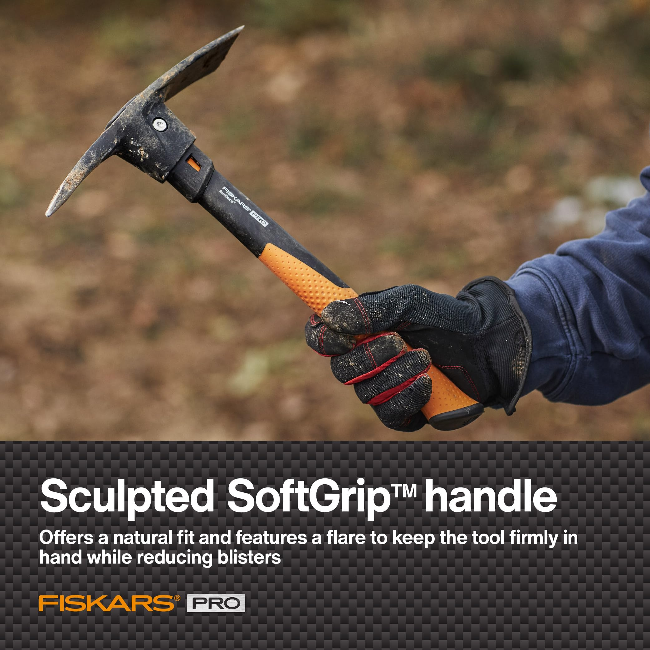 Eine Hand im Arbeitshandschuh hält einen Fiskars Pro Pickel mit ergonomischem Griff vor verschwommenem Hintergrund.