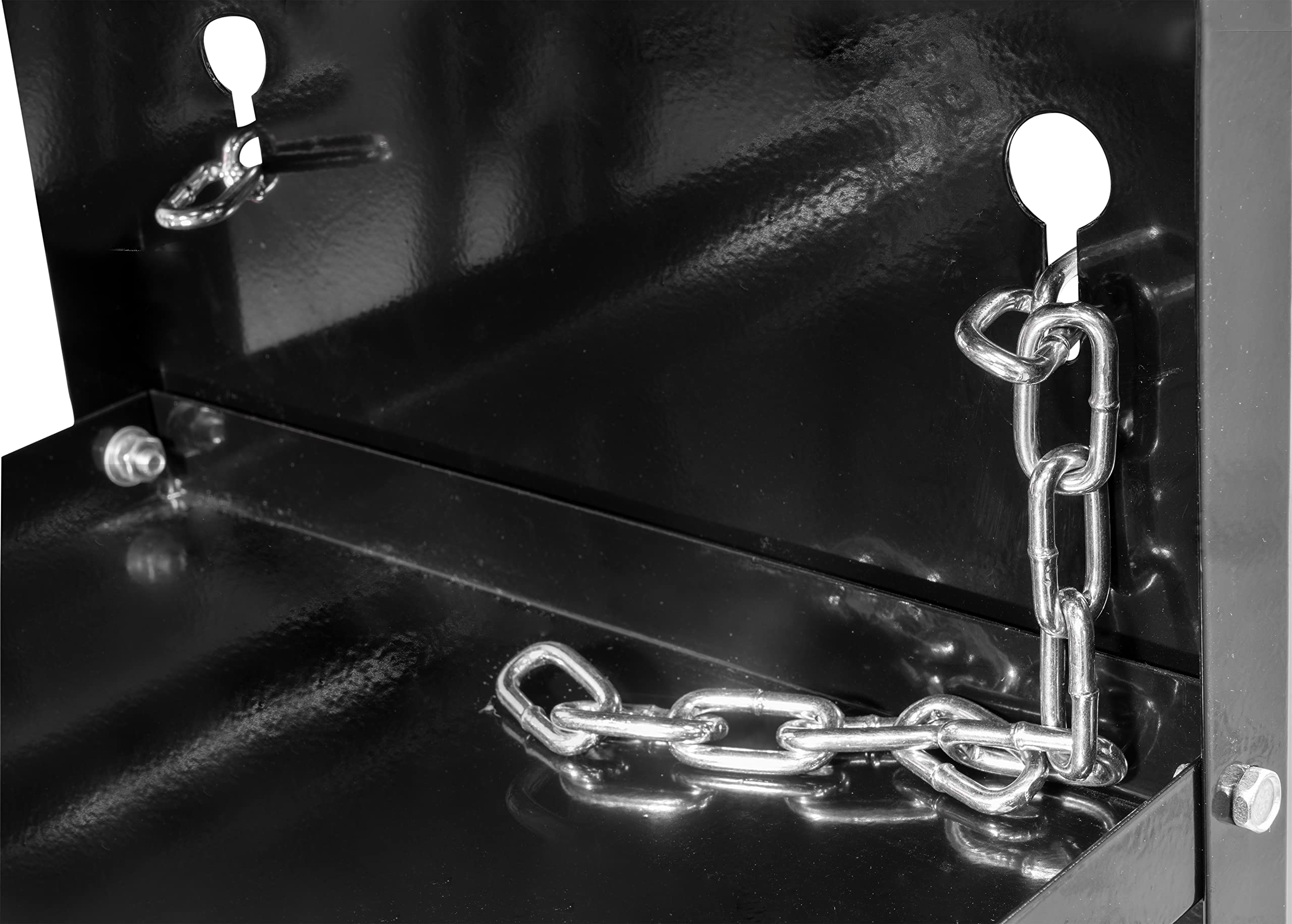 Eine glänzende Metallkette ist in ein Schlüsselloch eines schwarzen Metallmöbels eingehängt.