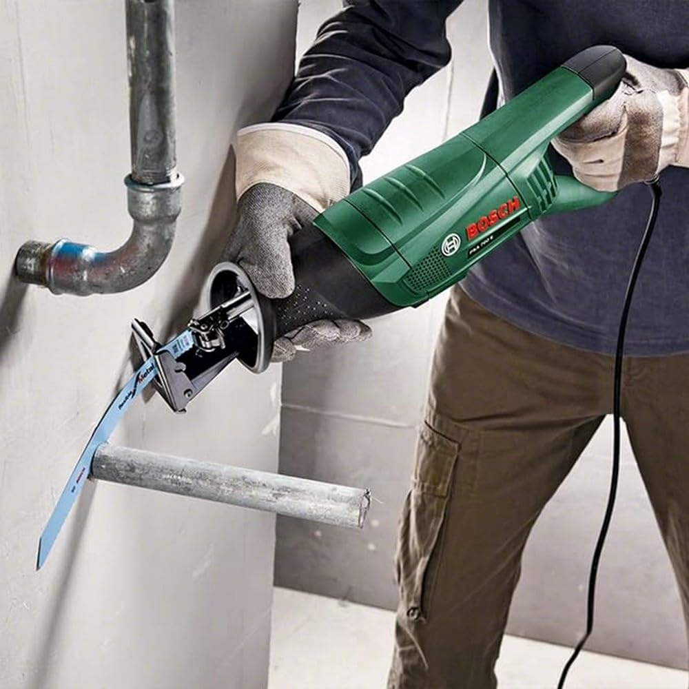 Una persona usa una sega reciprocante verde Bosch per tagliare un tubo di metallo.
