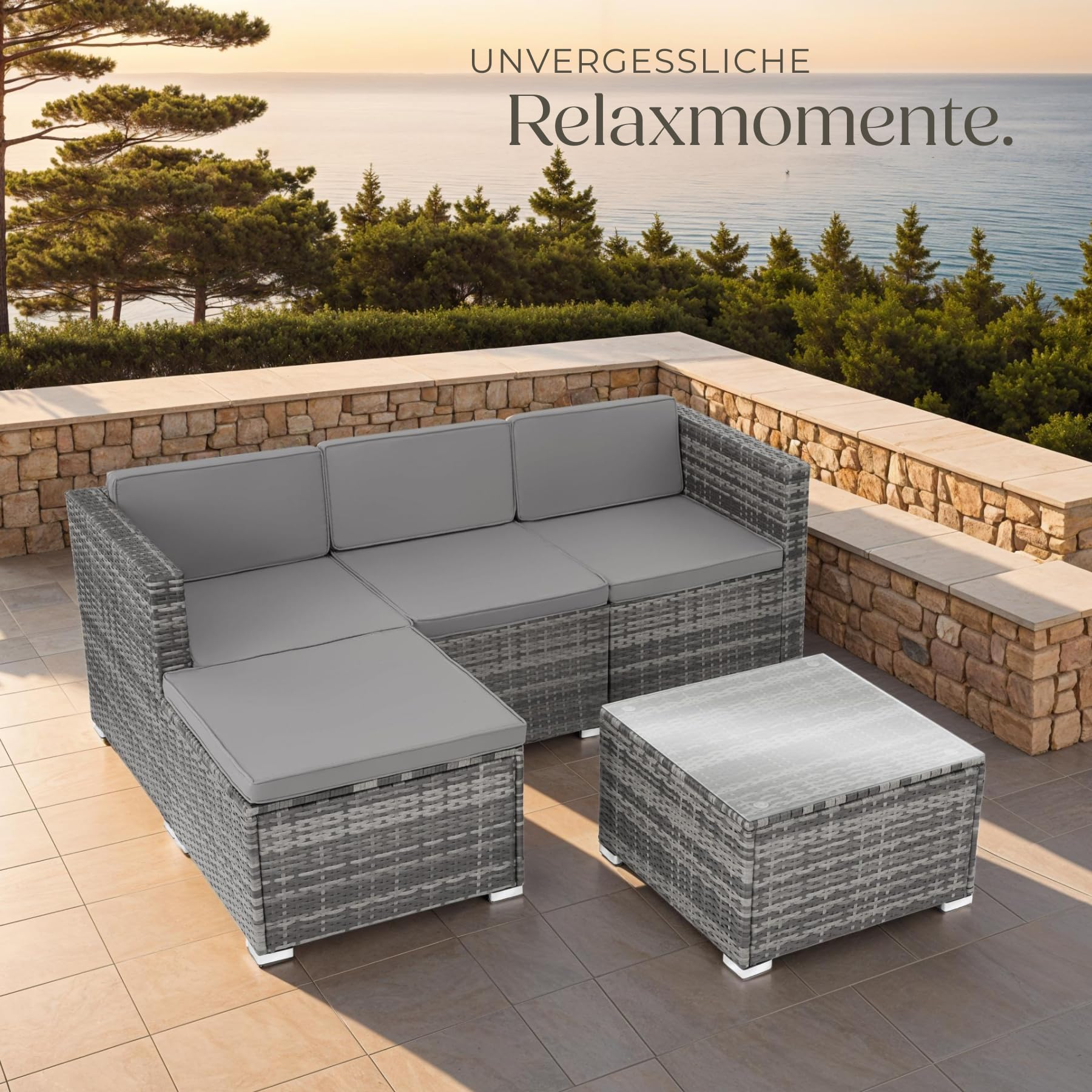Graues Rattan-Sofa mit passendem Hocker und Tisch auf einer Terrasse mit Meerblick.