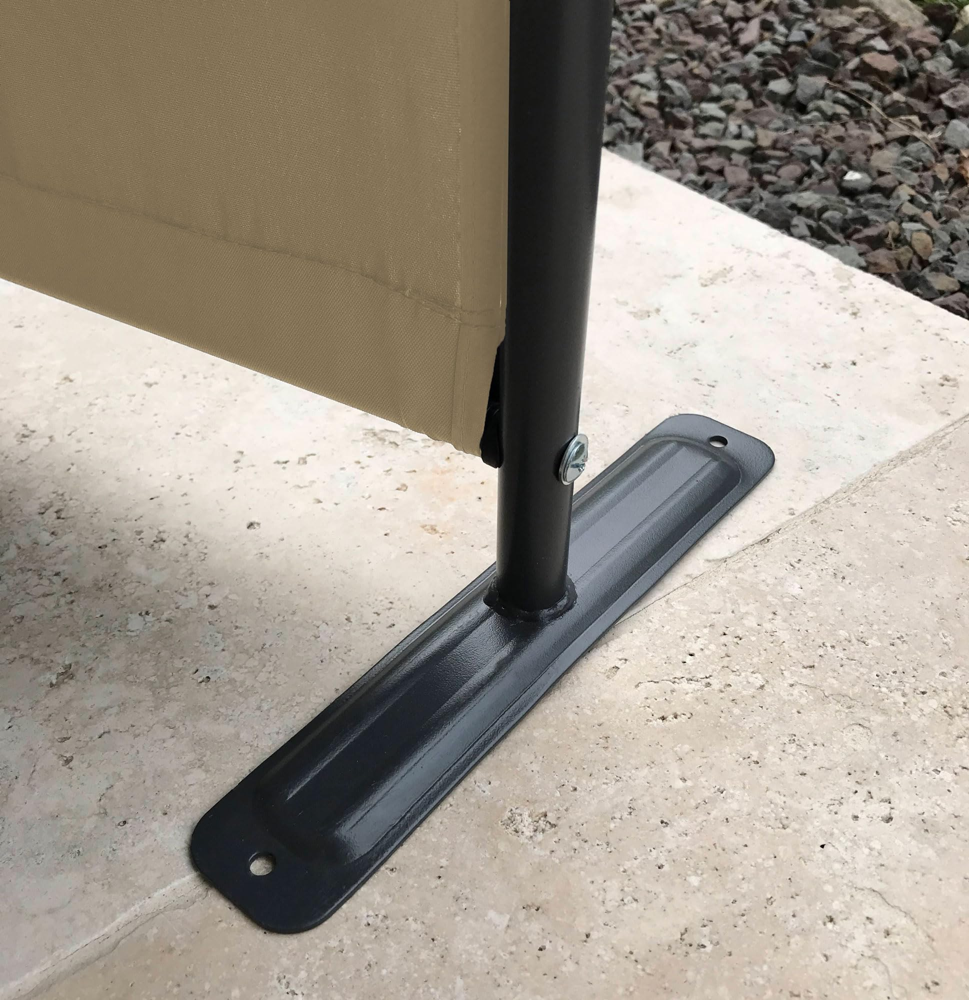 Ein schwarzer Metallpfosten eines beigen Stoffschirms ist mit einer rechteckigen Basis auf Stein verschraubt.