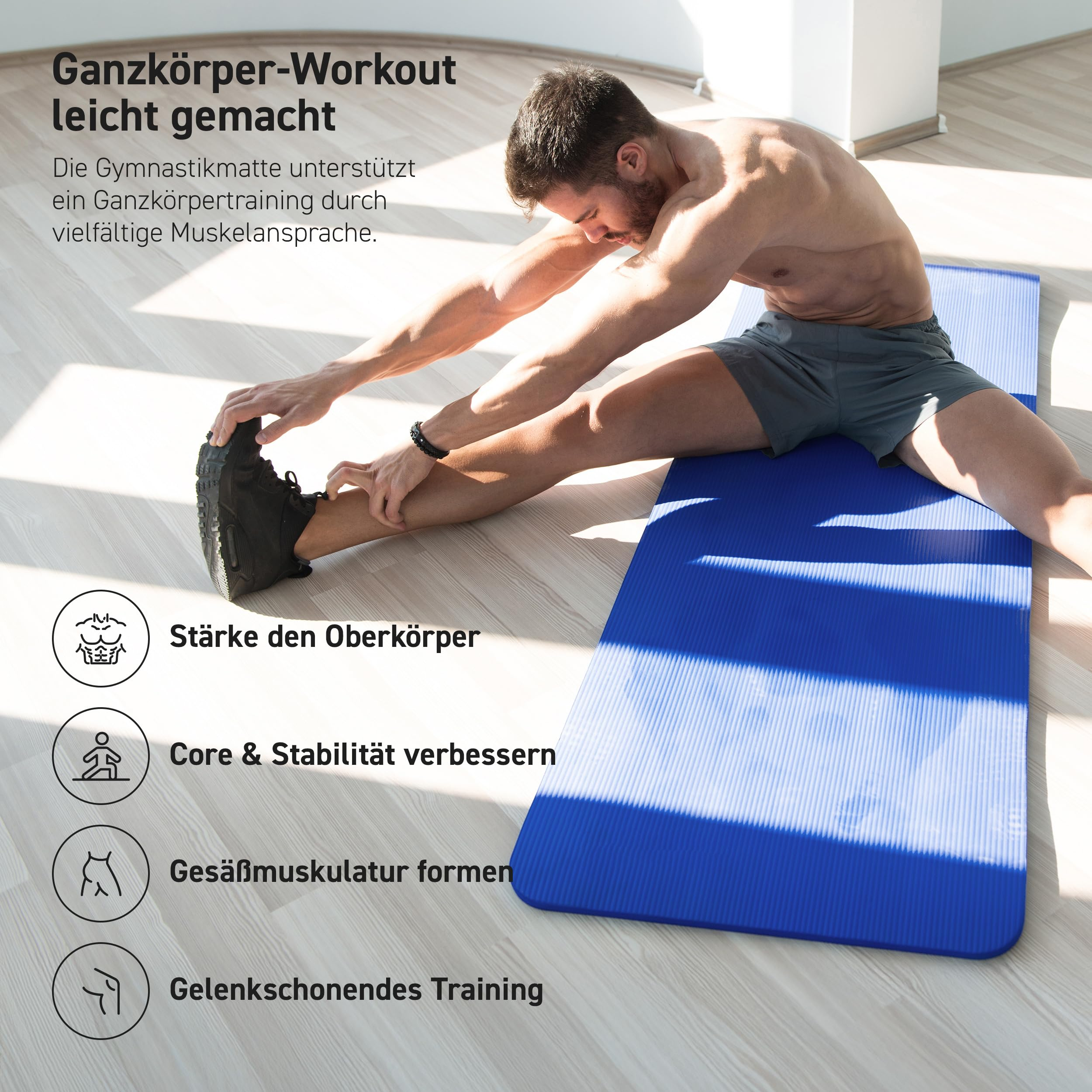 Ein oberkörperfreier Mann dehnt seine Beine auf einer blauen Gymnastikmatte in einem Raum.
