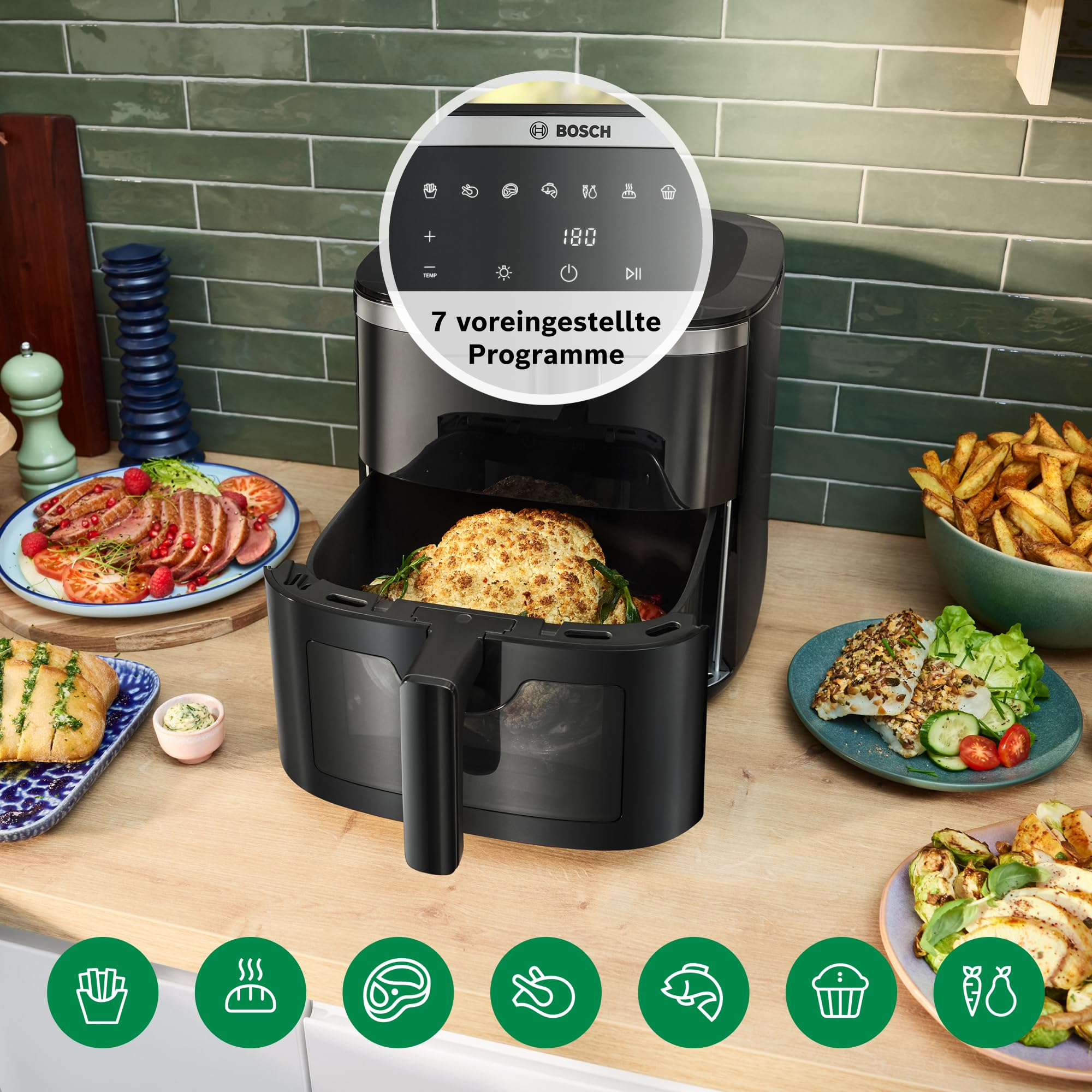 Friteuse à air Bosch noire sur plan de travail en bois avec nourriture et carreaux verts.