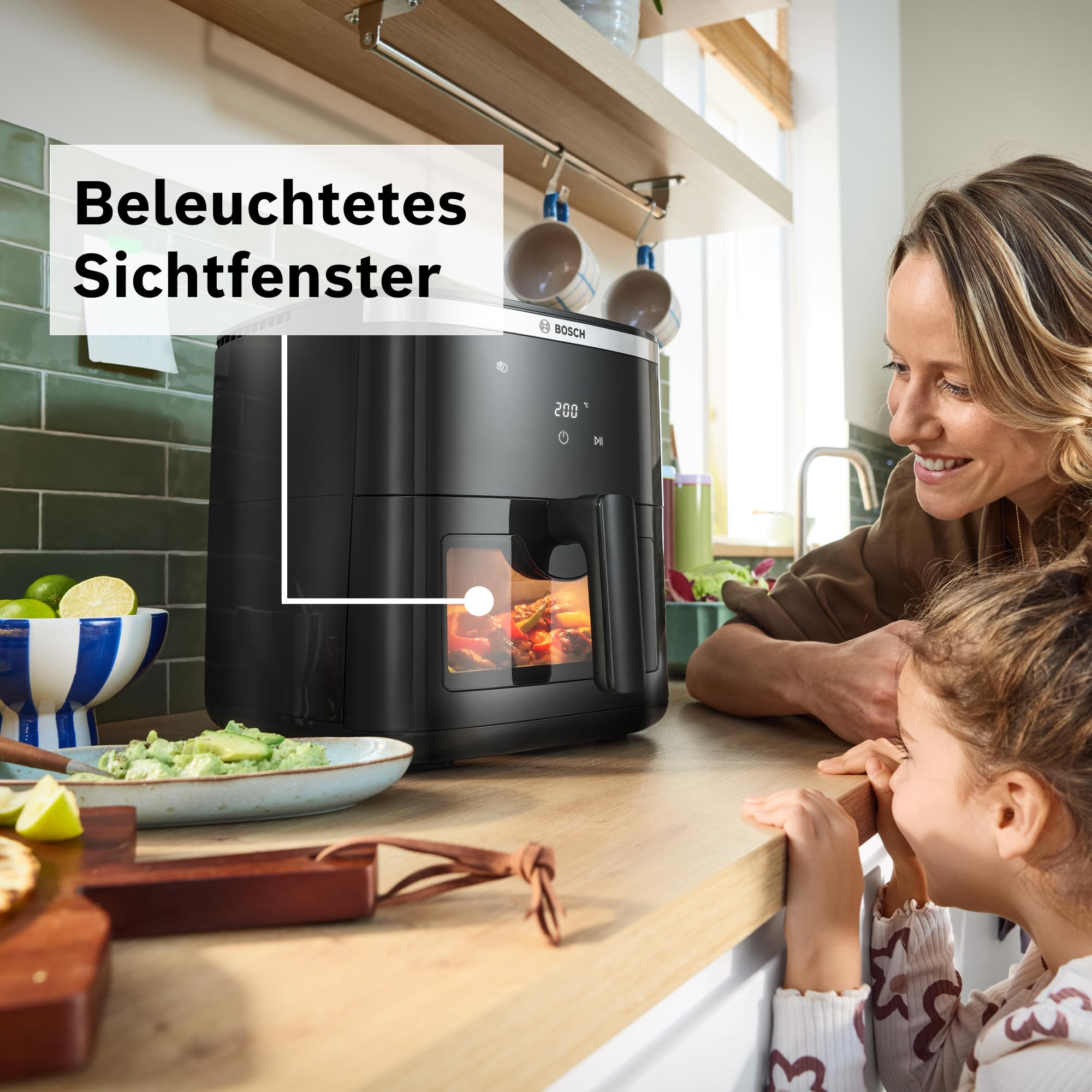 Mère et fille regardant la friteuse sans huile éclairée sur le comptoir.