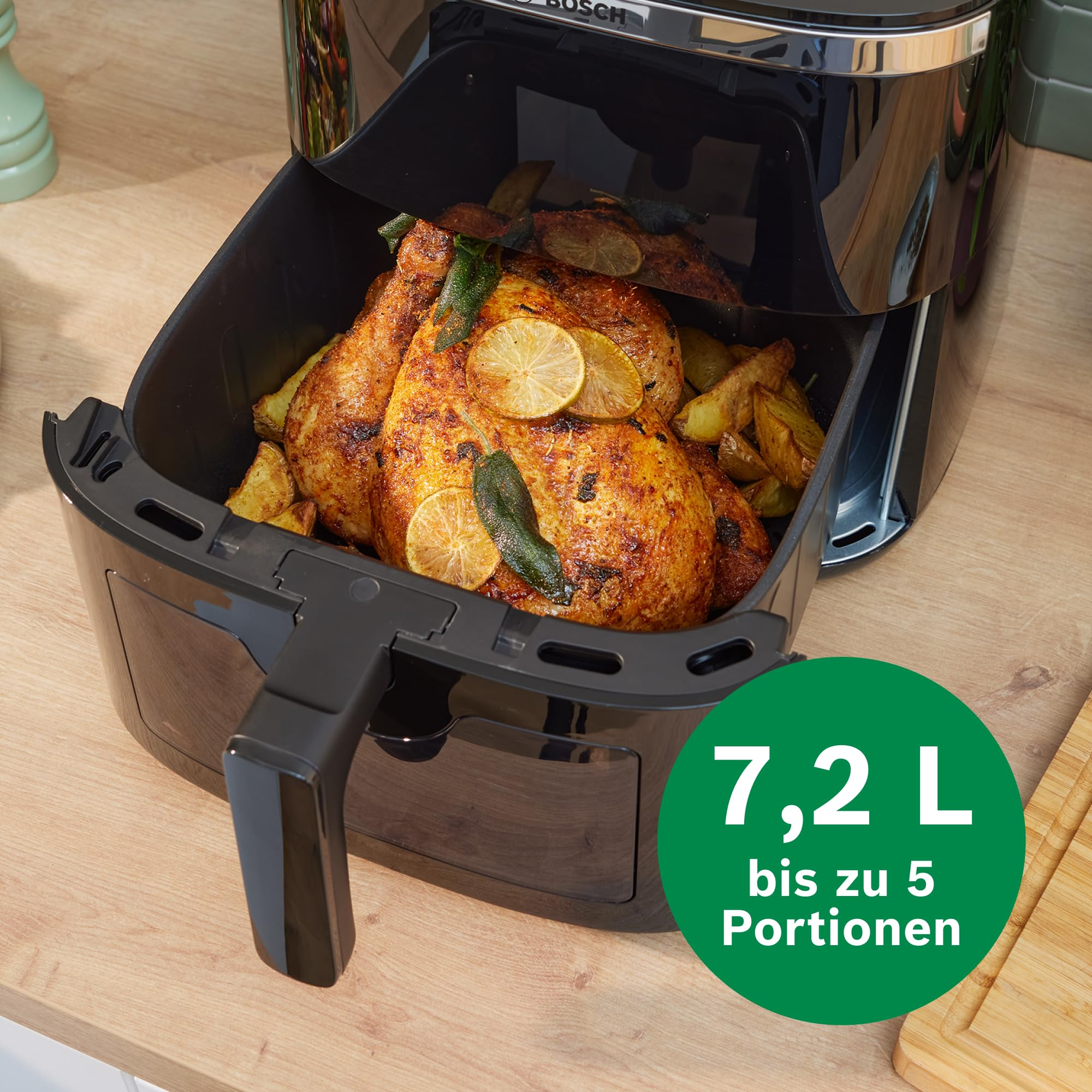 Une friteuse à air noire avec un panier ouvert montre un poulet rôti entier avec des tranches de citron et des herbes.