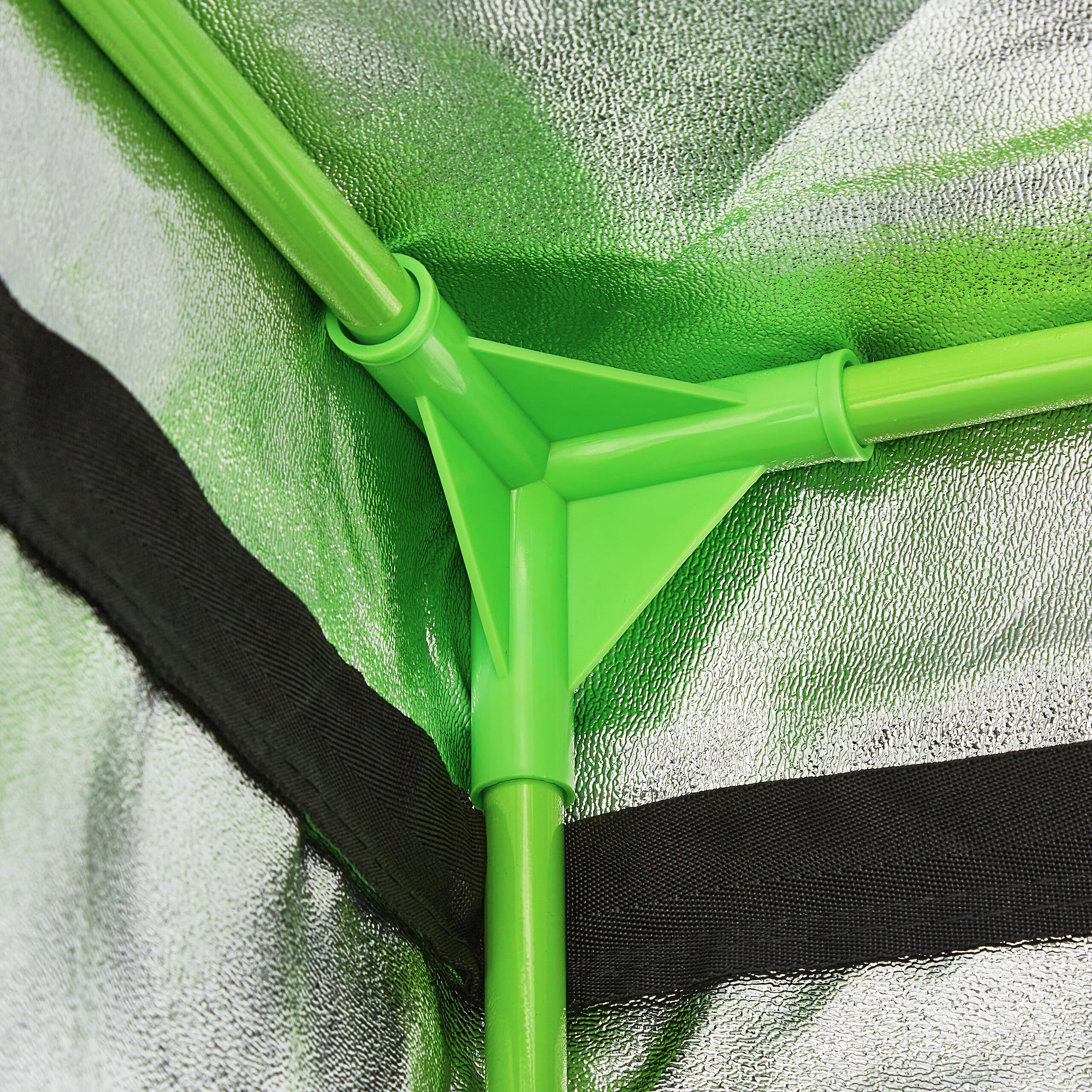 Connettore d'angolo in plastica verde che unisce tre pali all'interno di una tenda.