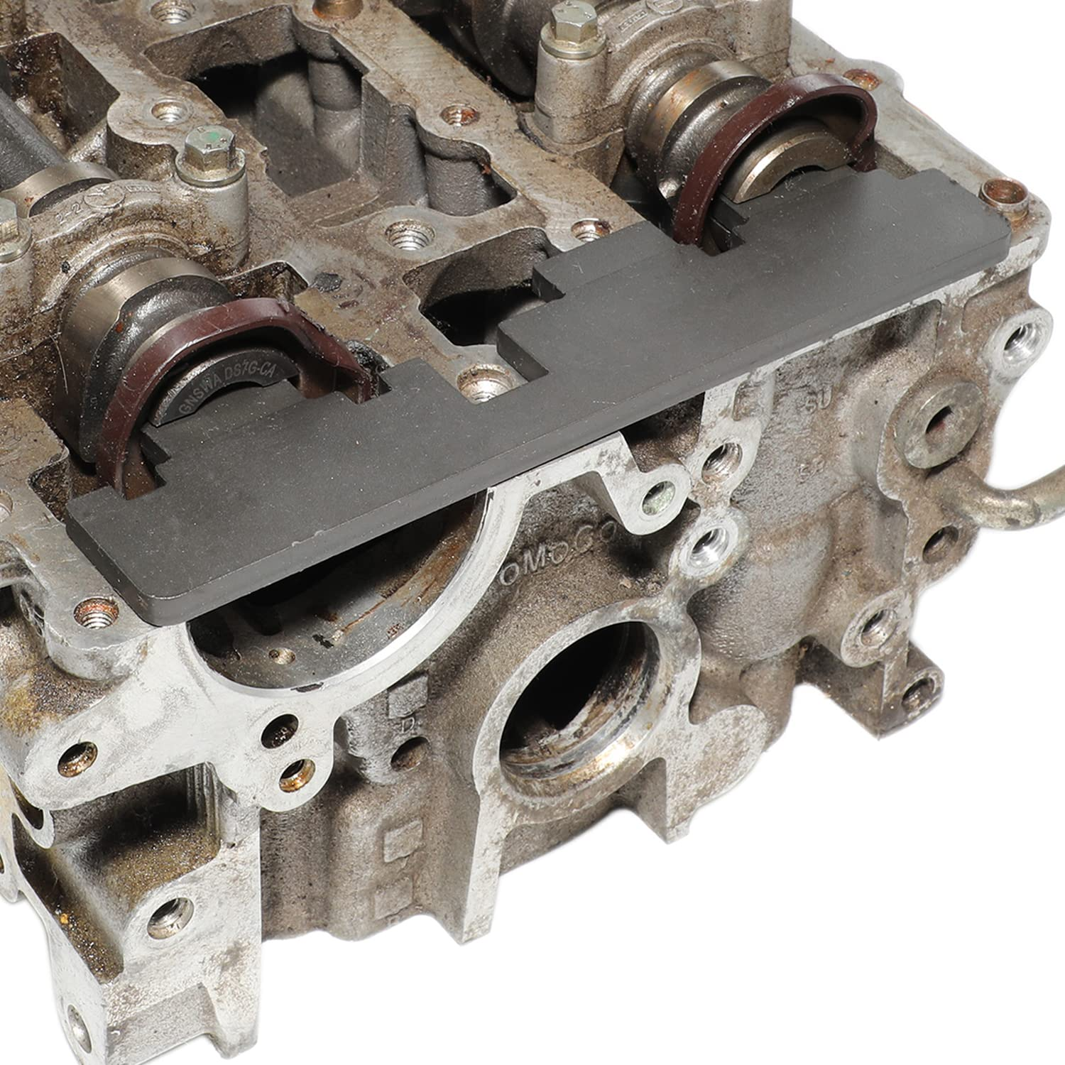 Ein graues Werkzeug ist auf dem Metallzylinderkopf eines Motors platziert.