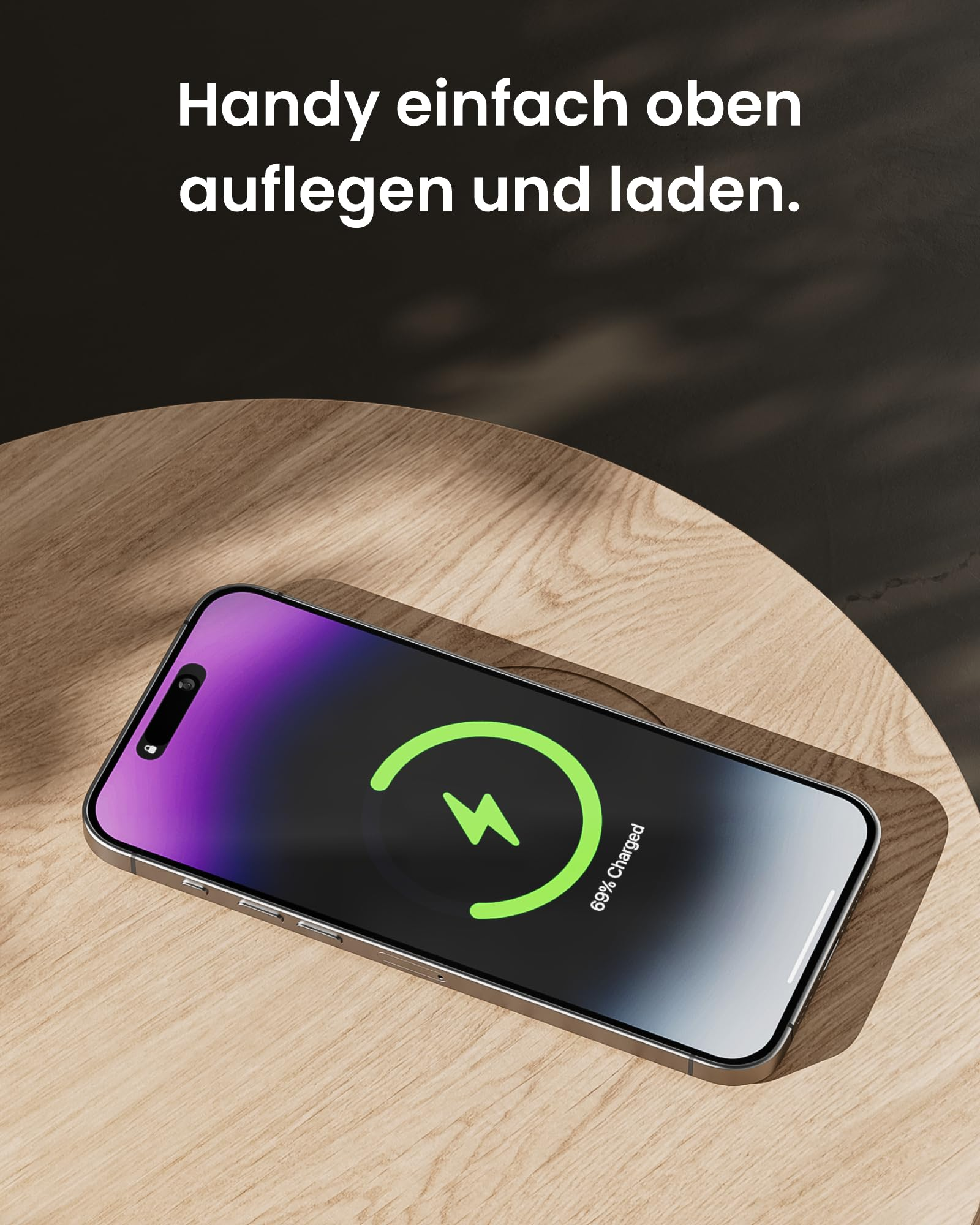 Ein Smartphone mit Ladeanimation liegt auf einem Holztisch, im Hintergrund deutscher Text.