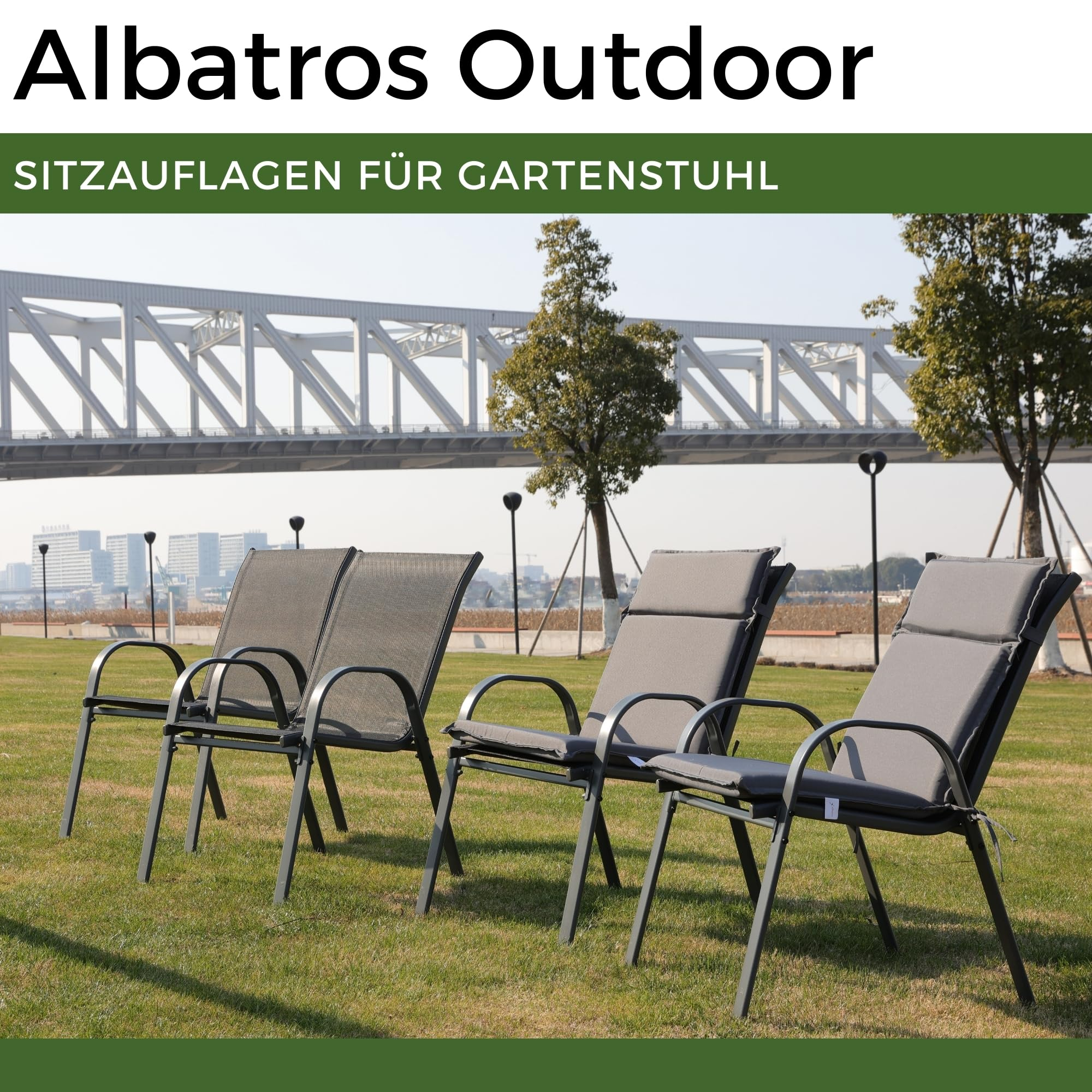 Vier Gartenstühle auf Rasen mit Brücke und Stadt im Hintergrund.